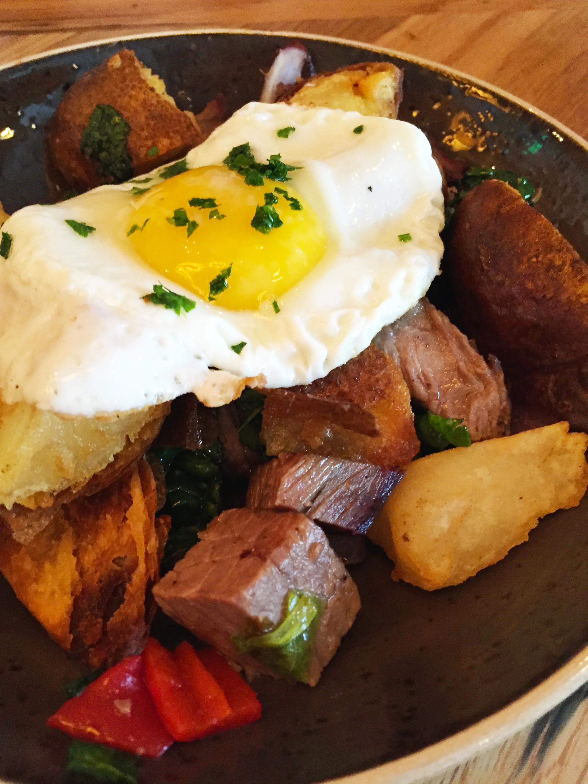 Breakfast Hash with onion, peppers, and charred romain with a fried egg. 