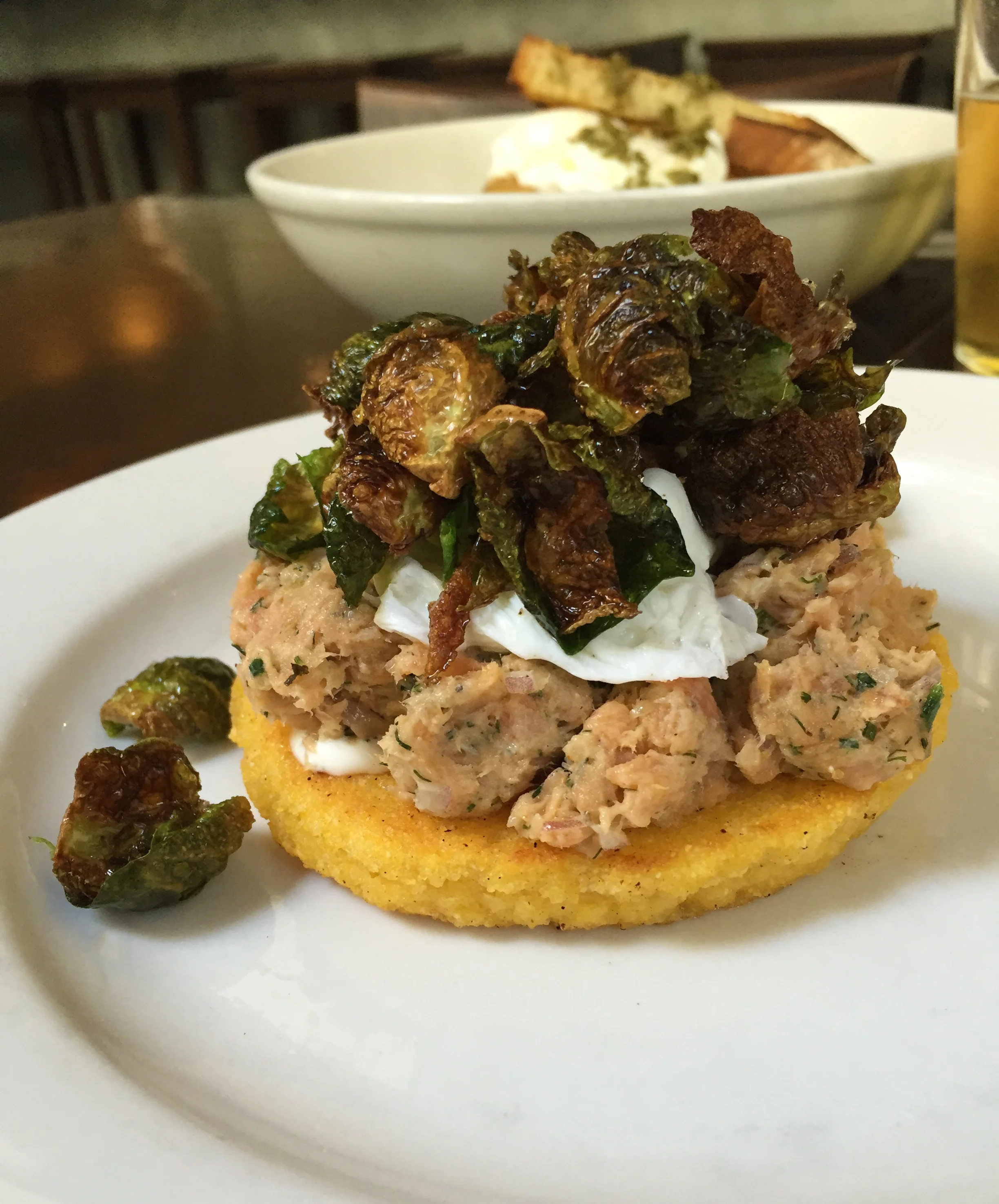 Johnny Cake with smoked trout salad, poached egg, and fried brussels sprout leaves.