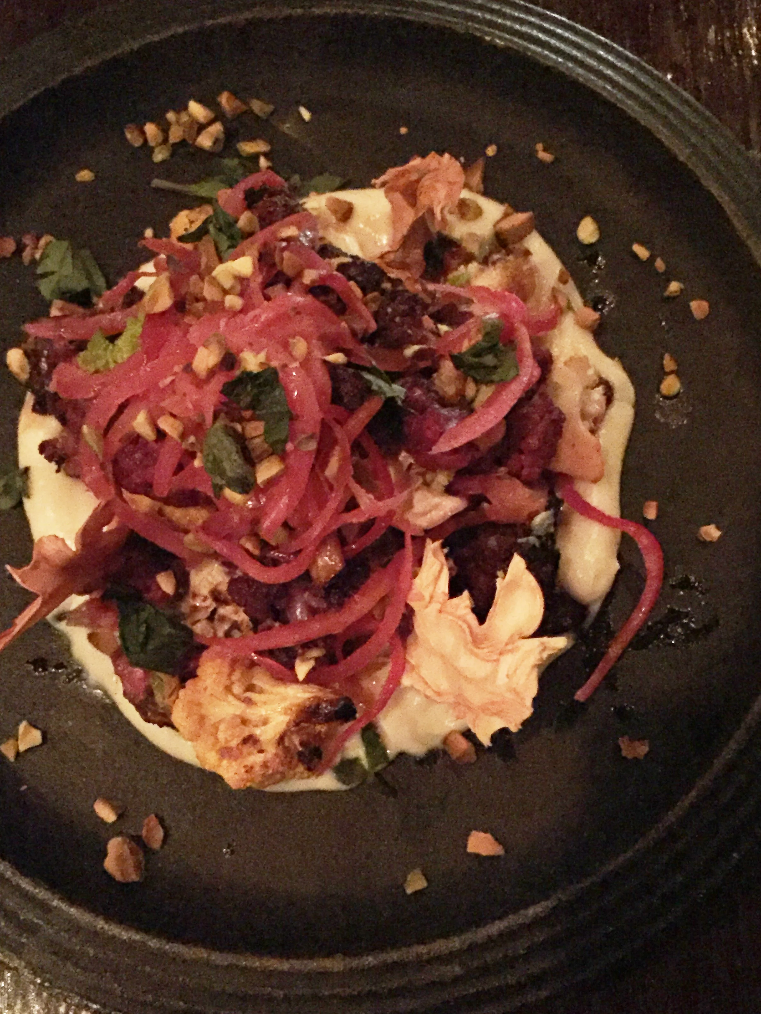 Blackened Cauliflower featuring cauliflower purée, roasted-blackened cauliflower, pickled red onion, Thai basil, toasted pistachios, and dehydrated cauliflower stem chips.