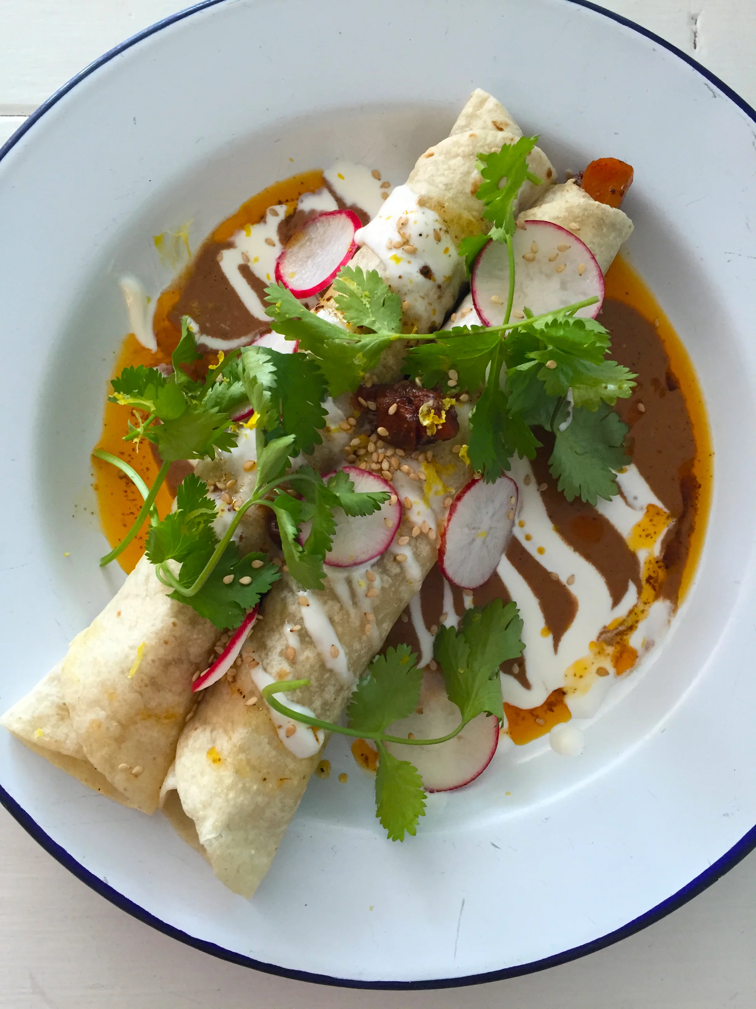 Carrot mole enchiladas with crème fraiche and cilantro.