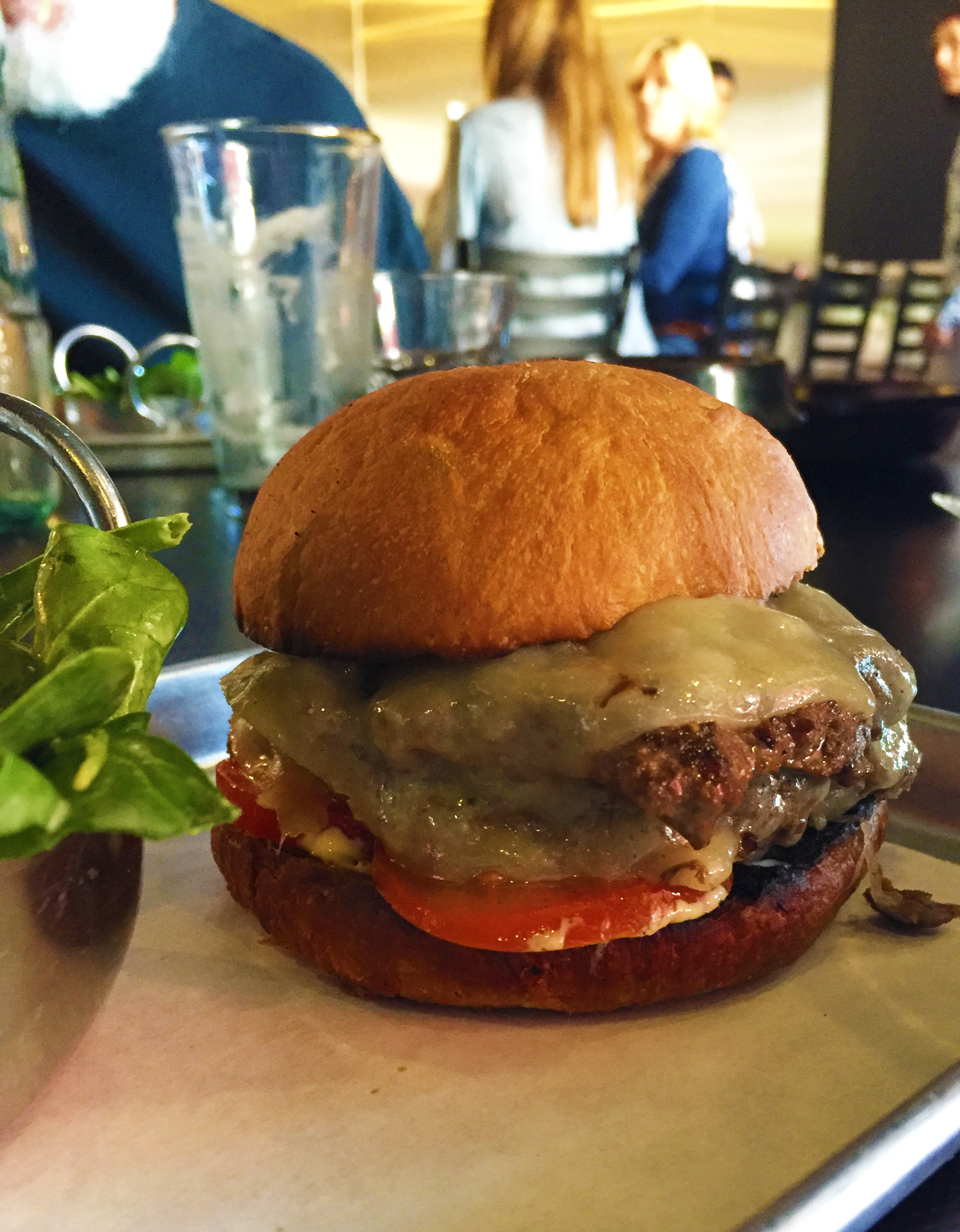 Cheeseburger with cheddar, yellow mustard, onion, tomato, and pickles.