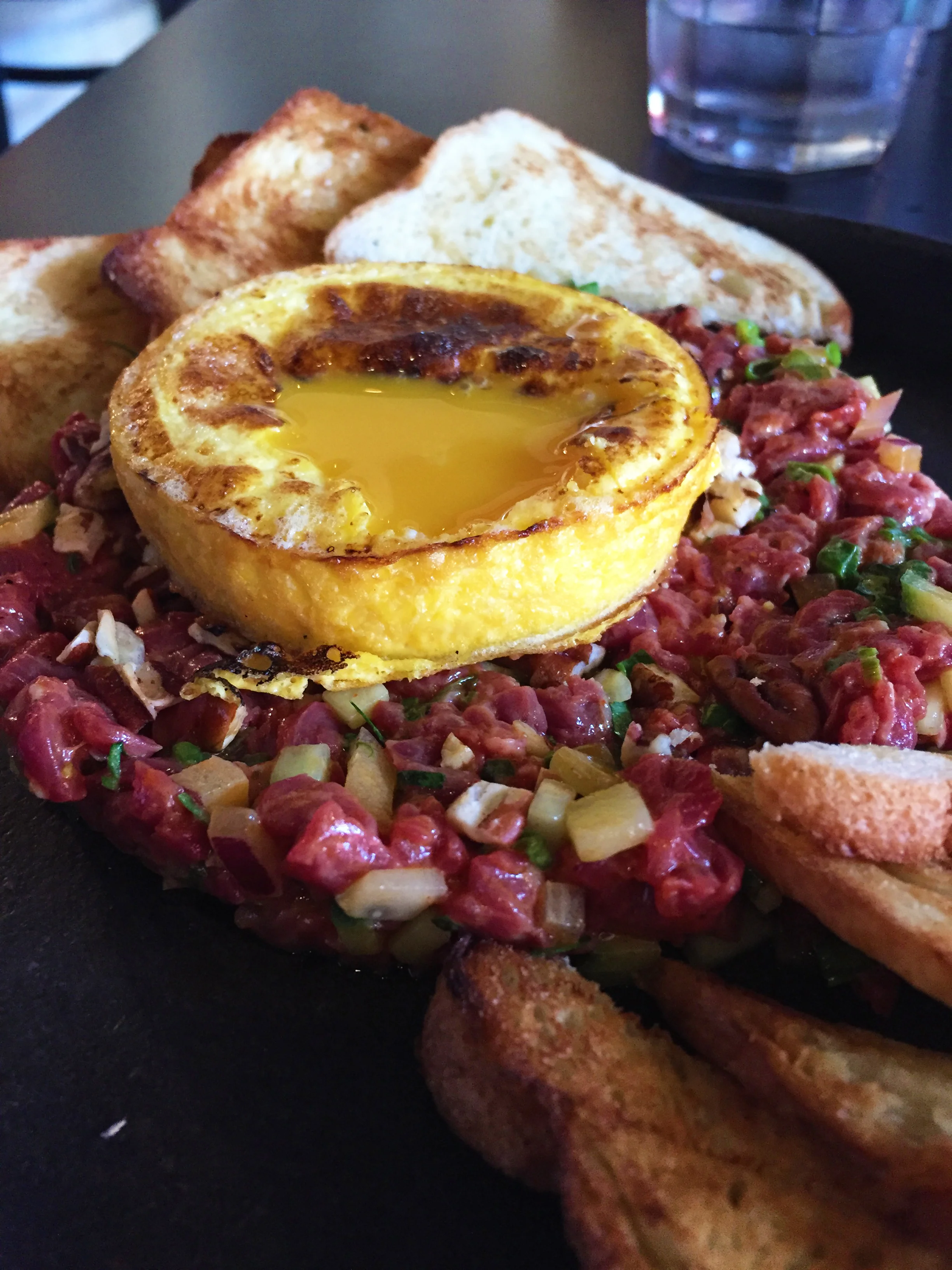 Steak Tartare with chermoula, toast, and seared egg yolk.