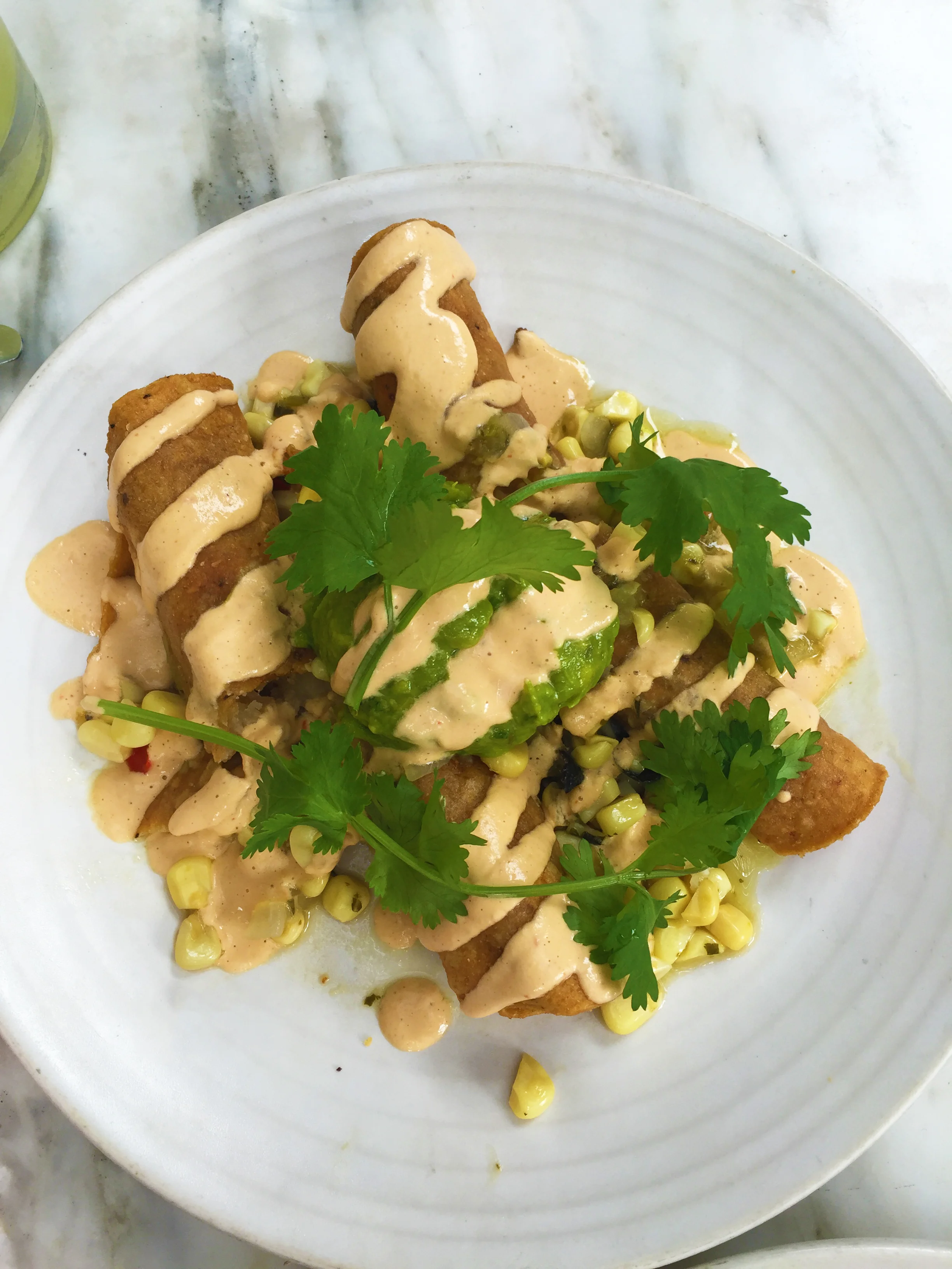 FLAUTAS DE PAPAS - two rolled tacos filled with potatoes - caramelized onion - corn relish - guacamole - cashew nacho cheese - cilantro