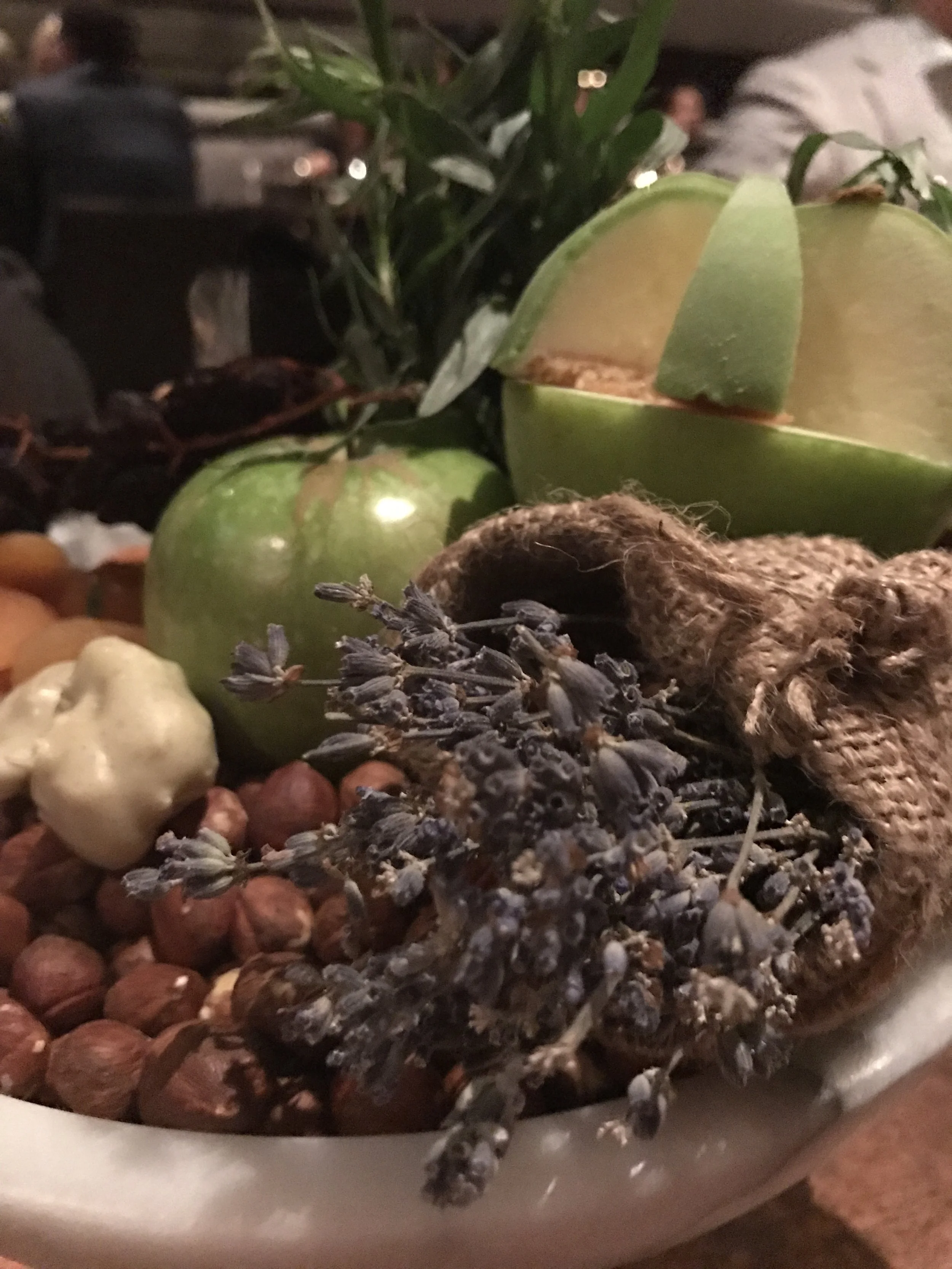 Bowl of fruit and herbs, with wrapped pieces of apricot taffy and lavender-dipped hazelnuts