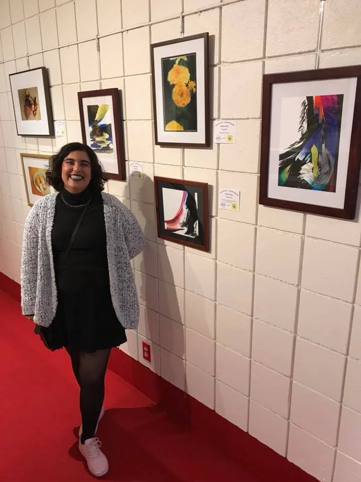image description: Meheen Ruby poses in front of a display of her recent abstract work on paper.