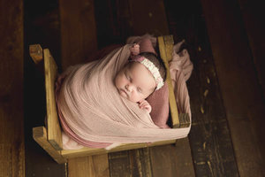 Newborn girl tucked into vintage bed prop