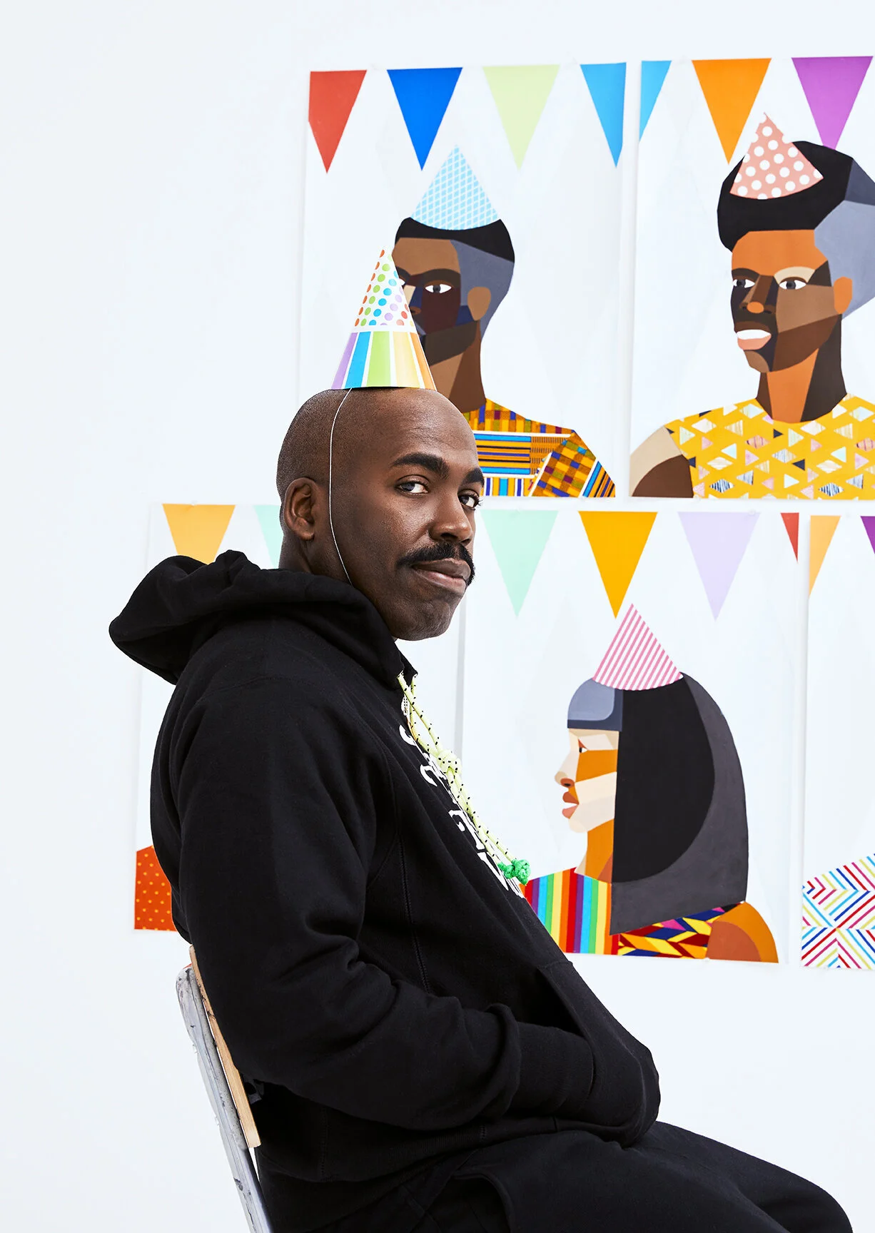 Editorial portrait of artist Derrick Adams seated before his figurative paintings, photographed by Christopher Garcia Valle