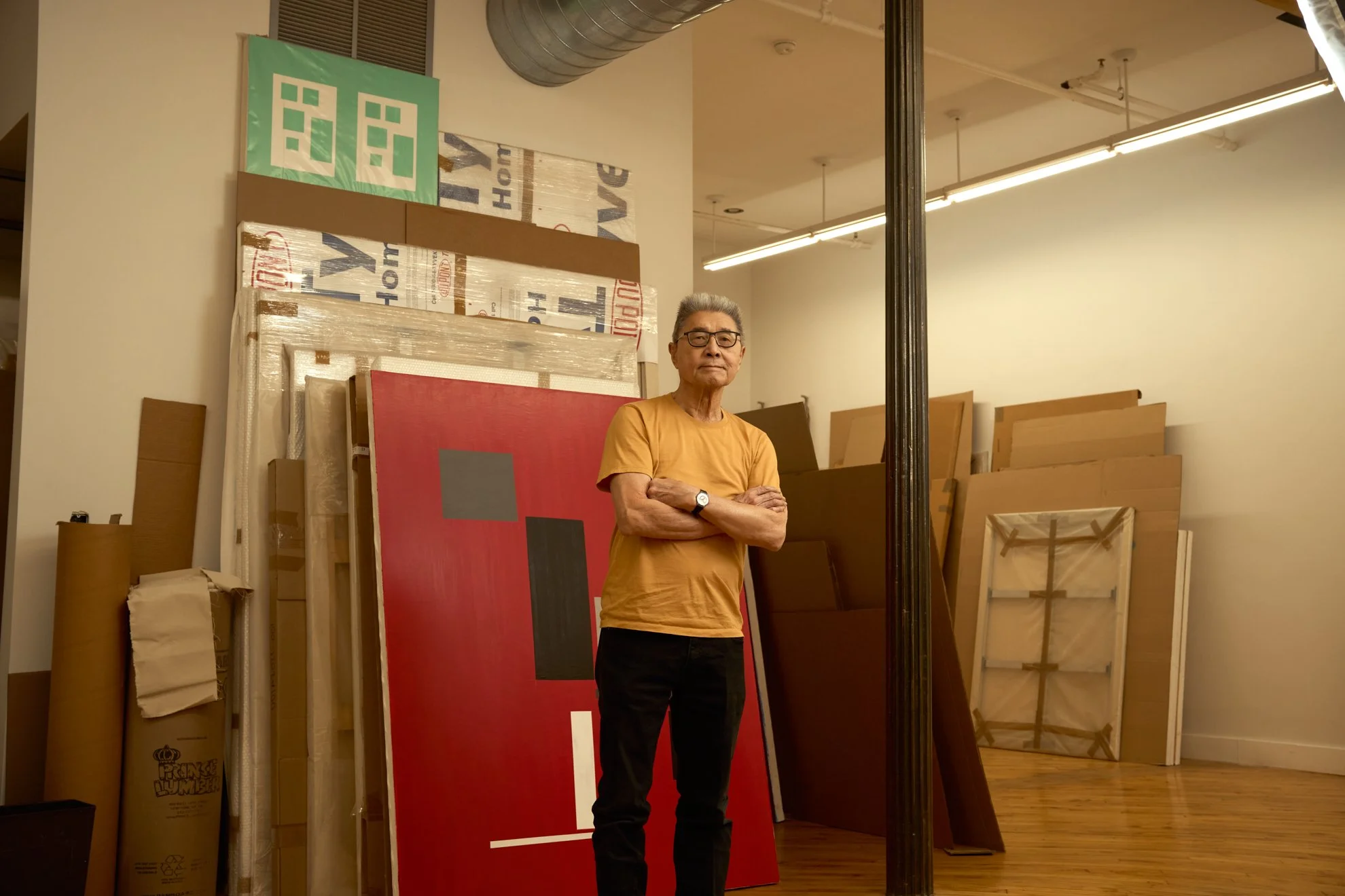 Editorial portrait of artist David Diao in his studio among his paintings and stored works, photographed by Christopher Garcia Valle