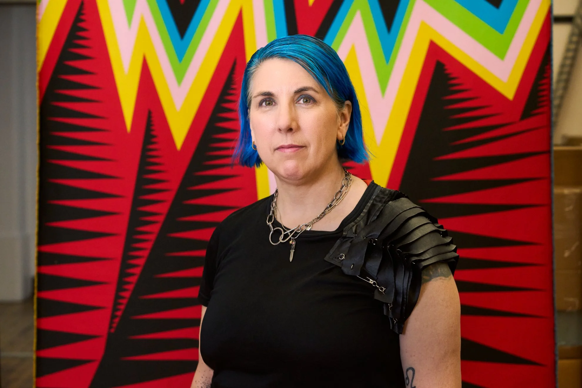 Editorial portrait of artist Liz Collins before one of her bold geometric textile works, photographed by Christopher Garcia Valle