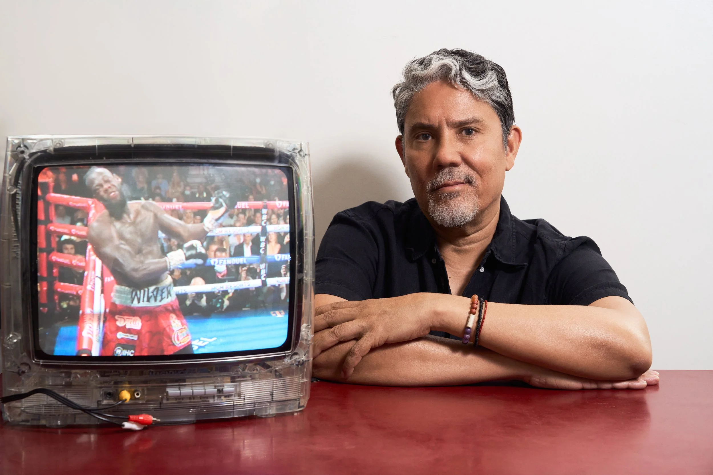 Editorial portrait of artist Paul Pfeiffer beside his work Caryatid (Wilder III), a modified video on a vintage television showing a boxing match, photographed by Christopher Garcia Valle