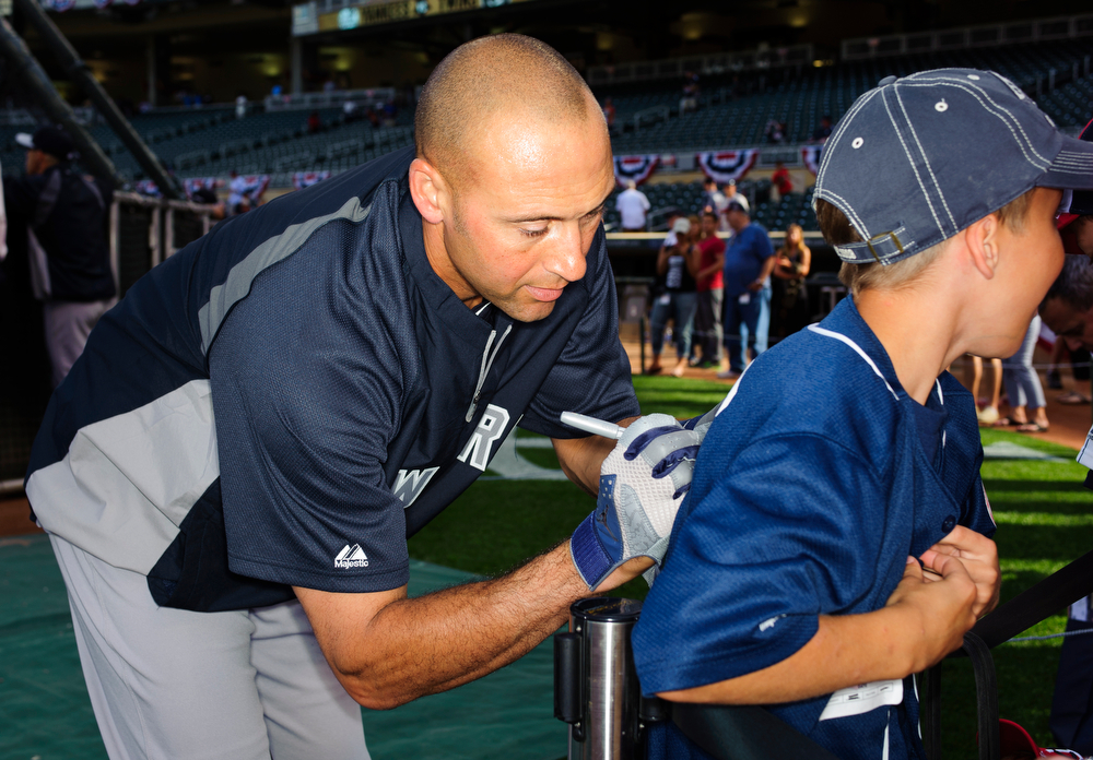  Derek Jeter #2 of the New York Yankees signs an autograph for a fan during batting practice before the game against the Minnesota Twins on July 3, 2014 at Target Field in Minneapolis, Minnesota.   (Photo by Hannah Foslien/Getty Images)  