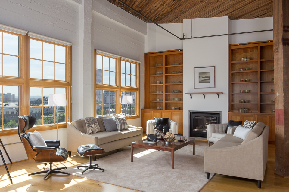 This is a composite of 4 images - 1 ambient interior, 1 with 2 flashes (1 bounced camera left and 1 shoot-through umbrella camera right), 1 with a flash &STU far camera right lighting up the book case, back of couch and wood beam, and finally, 1 to capture the window view.