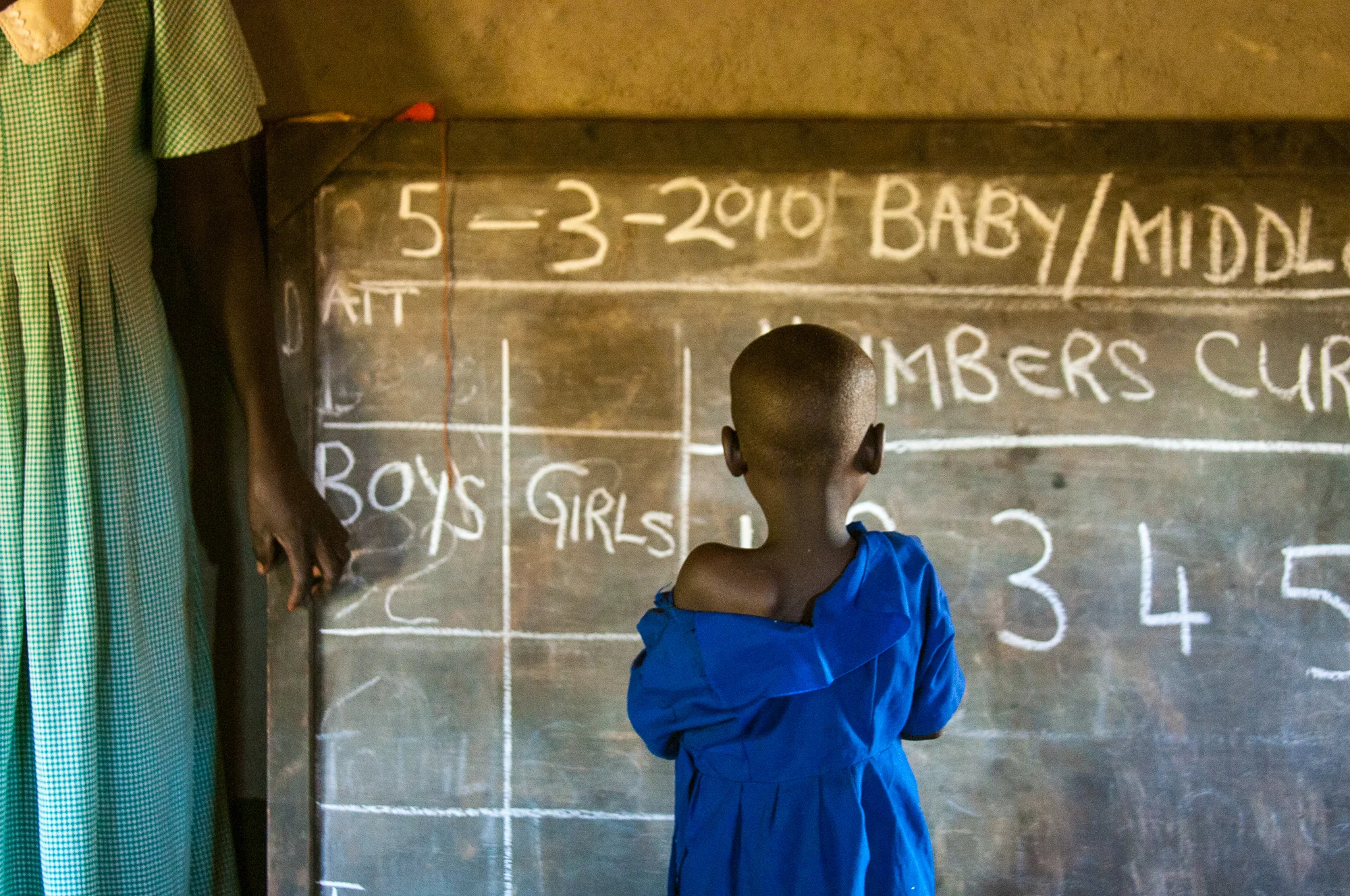 A young child in Lira, Uganda learns her numbers. Her teacher gained her education through Obaya's educational program which assists in paying for education in the rural areas of Uganda. In return, part of the teachers salary goes to pay for another teacher to get a degree.