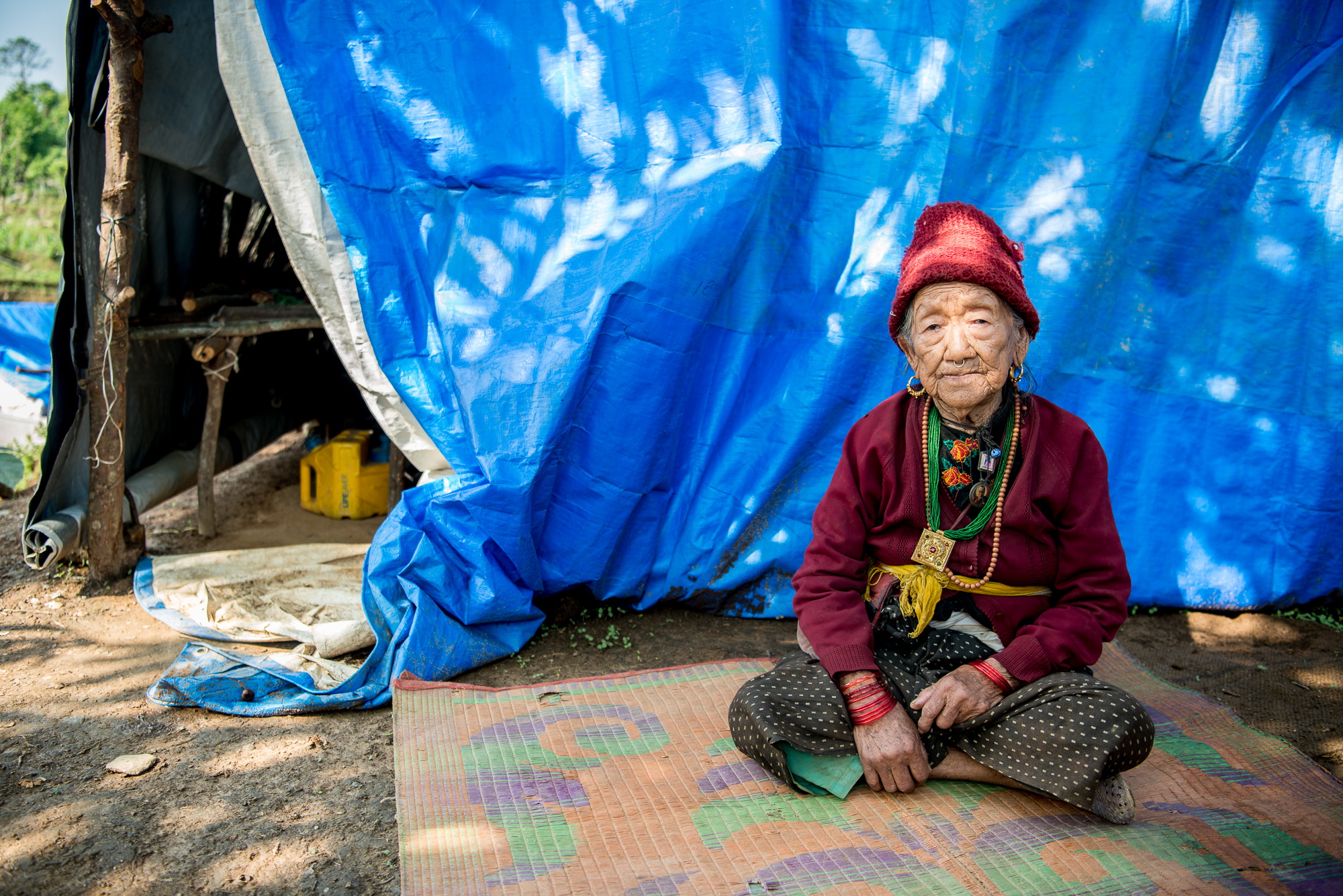 Moti Maya was only seventeen when she experienced her first earthquake¬, an 8.4M shock that struck Nepal on January 15, 1934. Eighty-one years later, her home was destroyed by the recent massive quake in 2015 that also killed four people in her small village. After two months of living in the destruction with very little food, Maya Moti left everything she knew and went by helicopter to start a new life in Dhola. She spent the last year living in a tent, but her spirit remains strong and positive. While she confirms that nothing remains for her family in their old village, she finds all these changes in her life exciting. She expects she will die soon but is pleased that her daughter, son, and grandchildren will now have a safe place to call home in Dhola. Moti Maya’s wish is that her community will live in harmony while undertaking their project of building their fifty-five new homes.