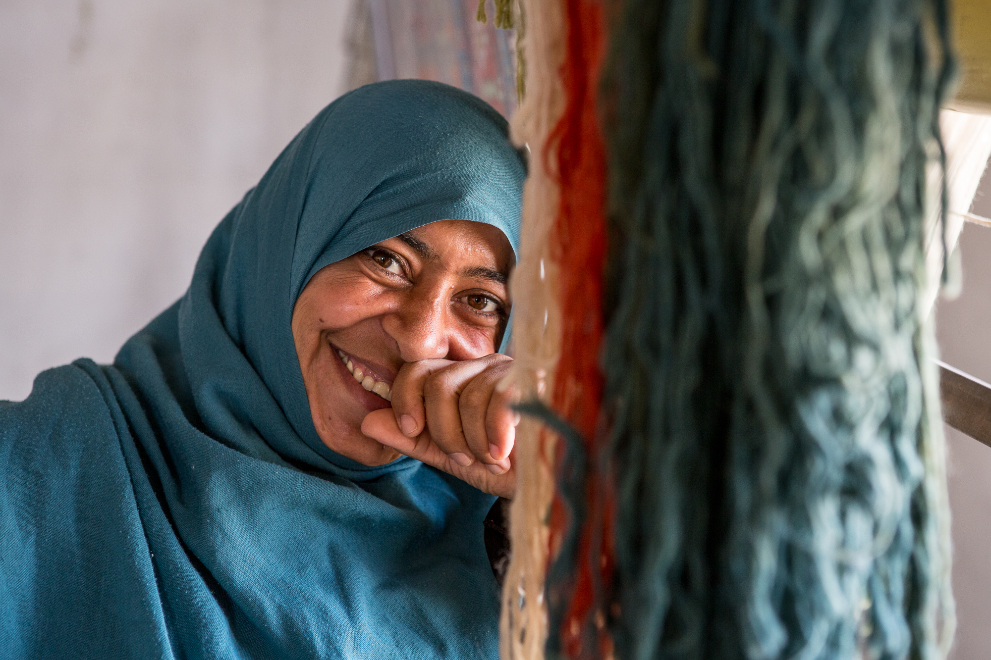 ©2016 The ANKA Cooperative. Neriman is in her early 40s and has six children. Unlike many of her relatives, she made it safely to the Adiyaman refugee camp in Southeastern Turkey. Neriman is college educated, and prior to the war she worked for many years as an accountant. But in the camps, there are no accounting jobs or freelancer websites to apply her trade. Idle time brings painful memories. She jumped at the chance to work at the carpet workshop. It’s a new skill, but she is learning – and just as important, she is earning a fair wage, same as her Turkish counterparts. Her smile shines despite the tragedy she has faced, and she is very grateful to have the chance to work again.