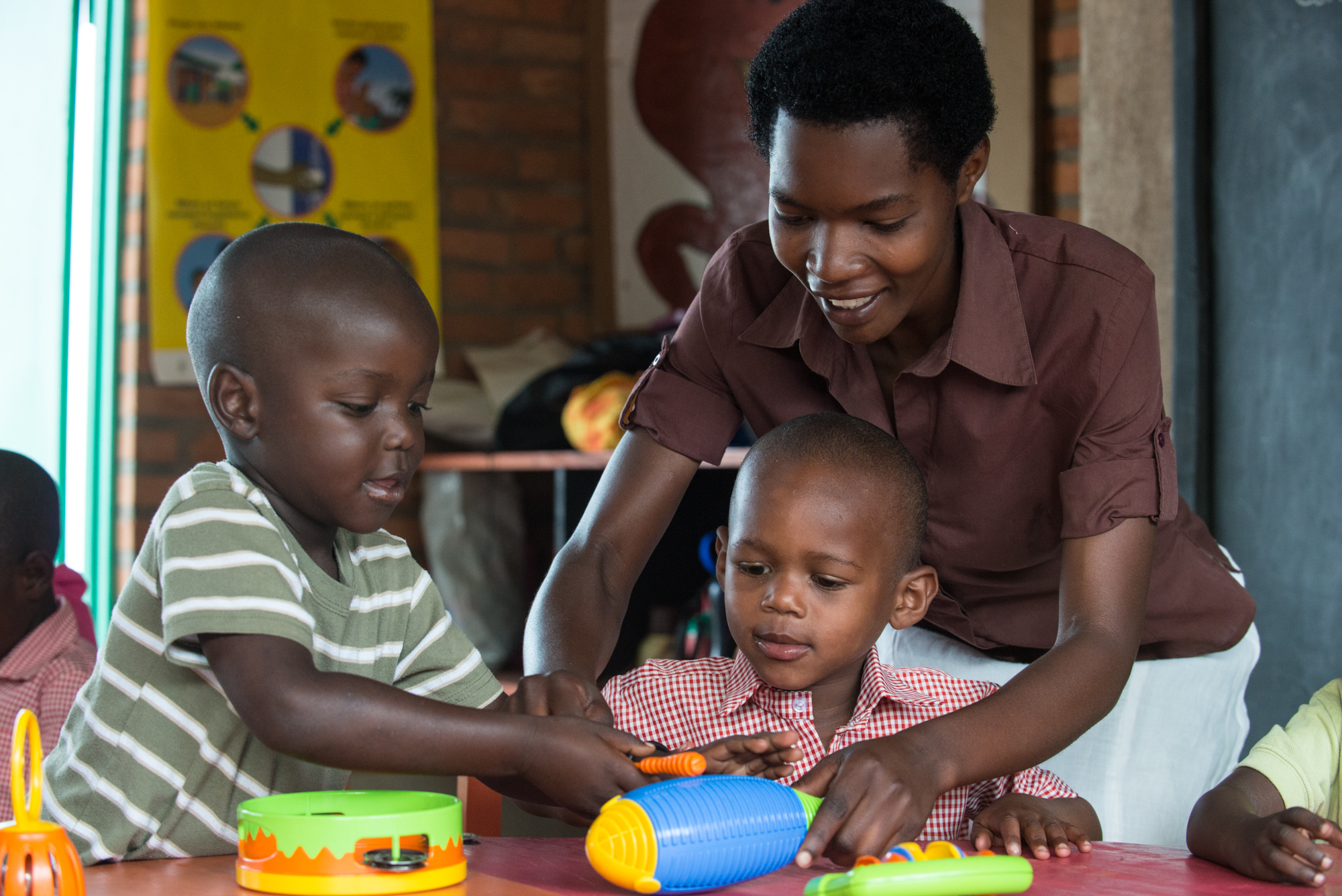 Jeanne Mukaruhirwa helps her students; Sacrifice & Eric make music in her pre-primary class in Kanyinya School in Rwanda.