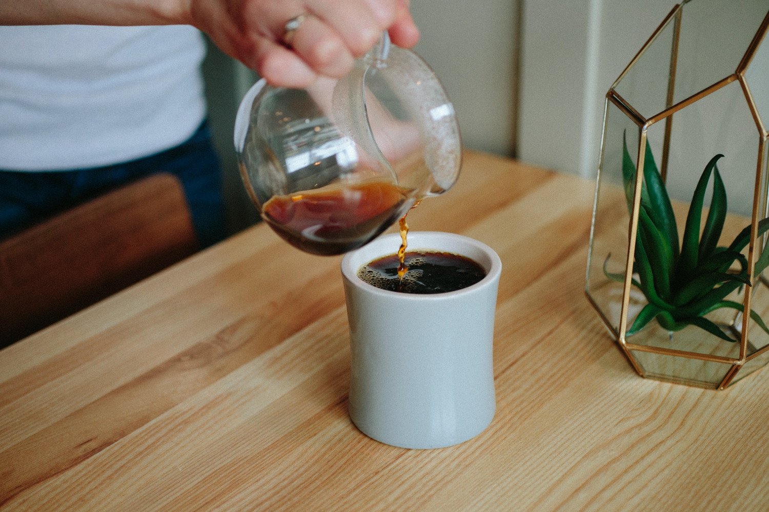 Image of a hand pouring a drip coffee in a mug