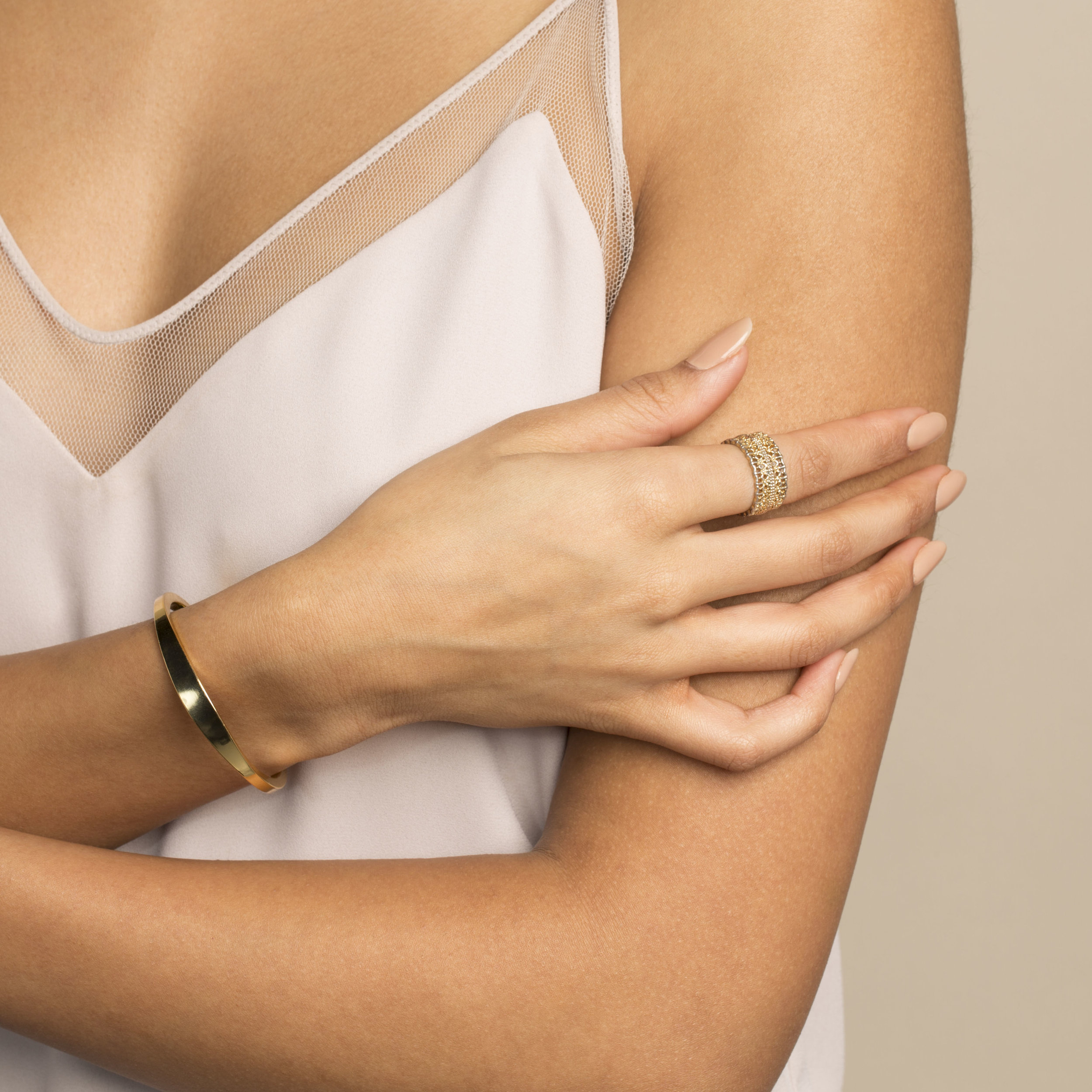 young brown skinned model with manicure wearing camisole, gold bracelet and ring  