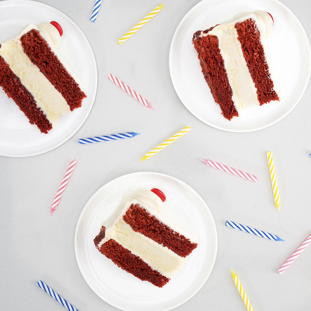  Three slices of red velvet cheesecake torte cake with scattered birthday candles  