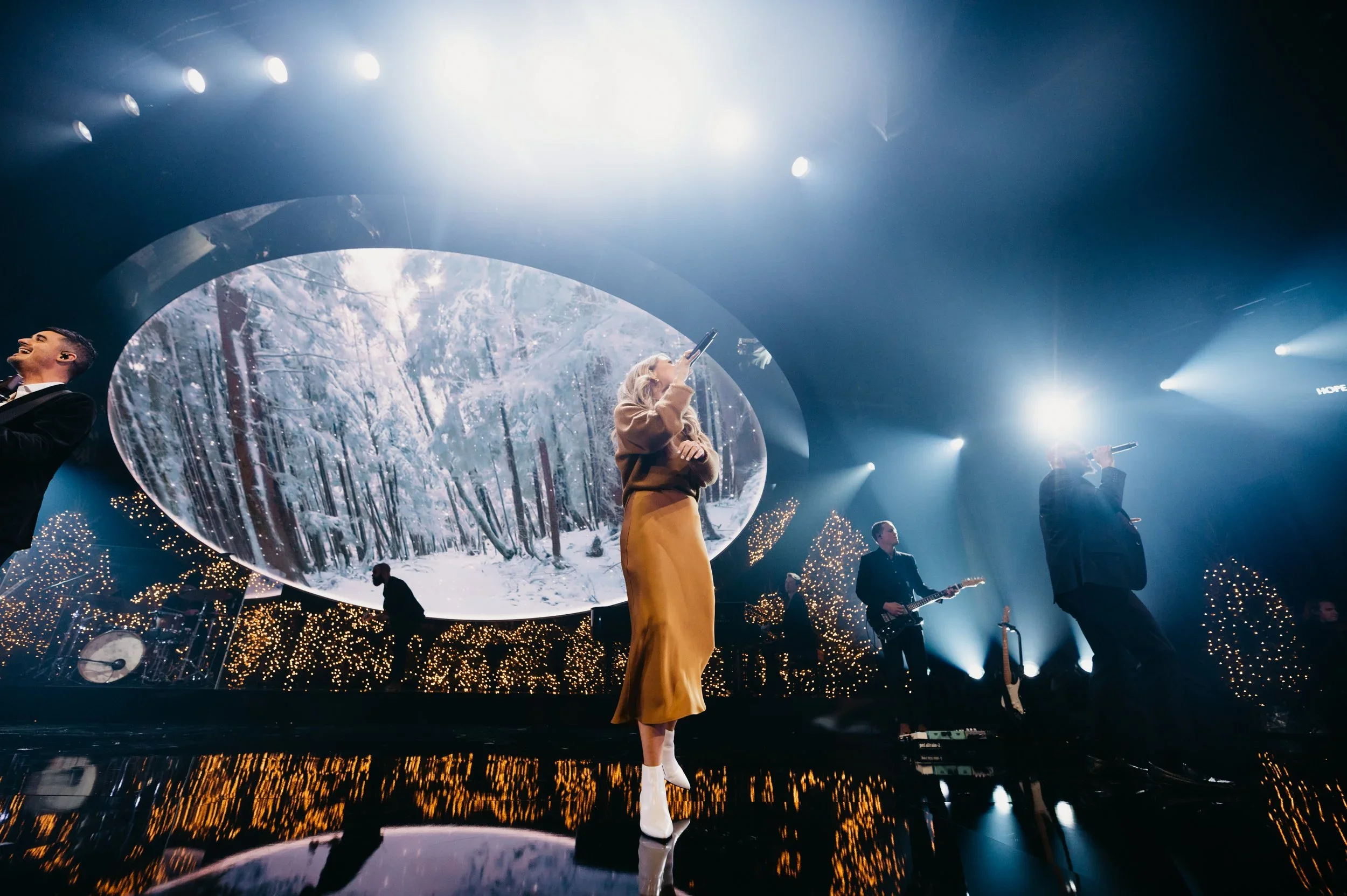 Immersive live event stage with circular scenic screen and forest-inspired visual backdrop.