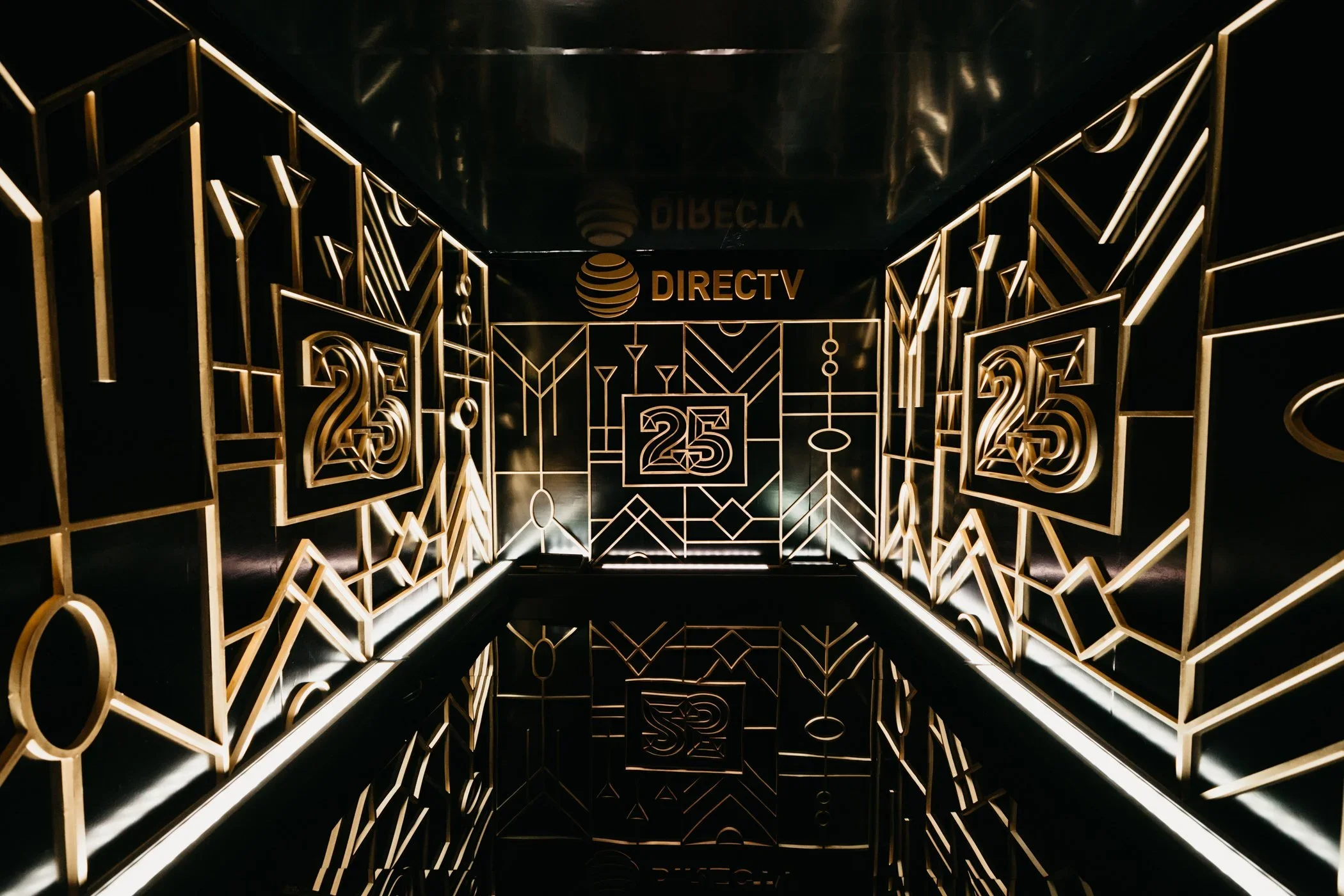 Illuminated branded tunnel installation with custom scenic walls and anniversary event graphics.