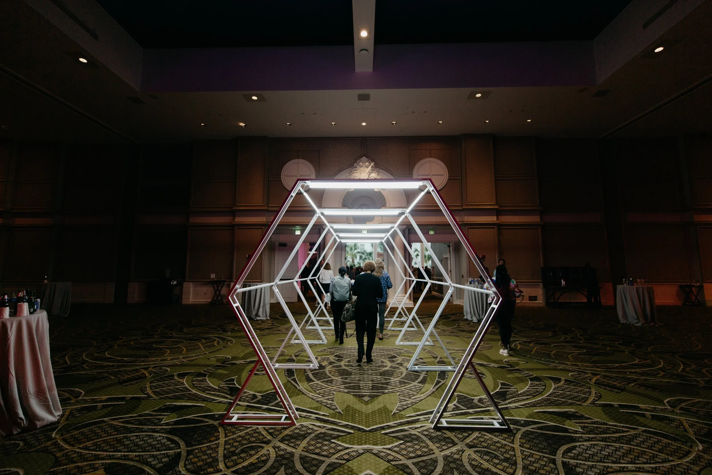 Geometric tunnel installation with custom scenic fabrication, lighting, and branded event design.