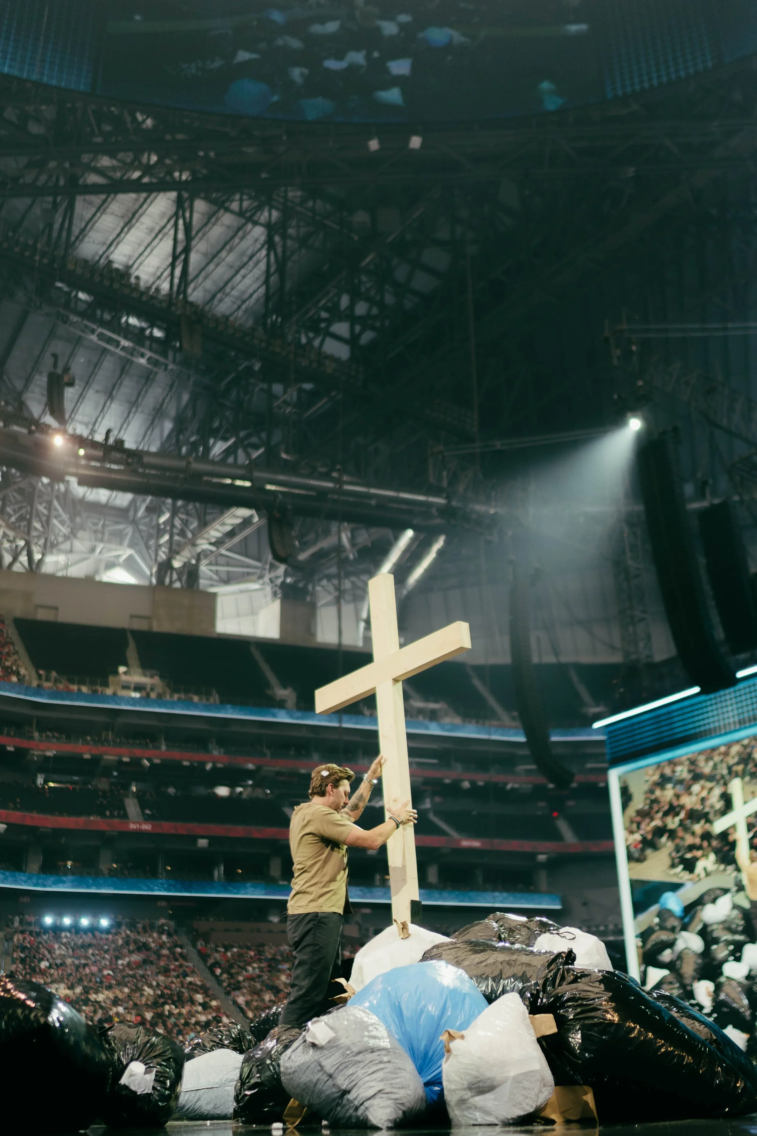 Live event stage with oversized cross prop, custom scenic elements, and large audience environment.