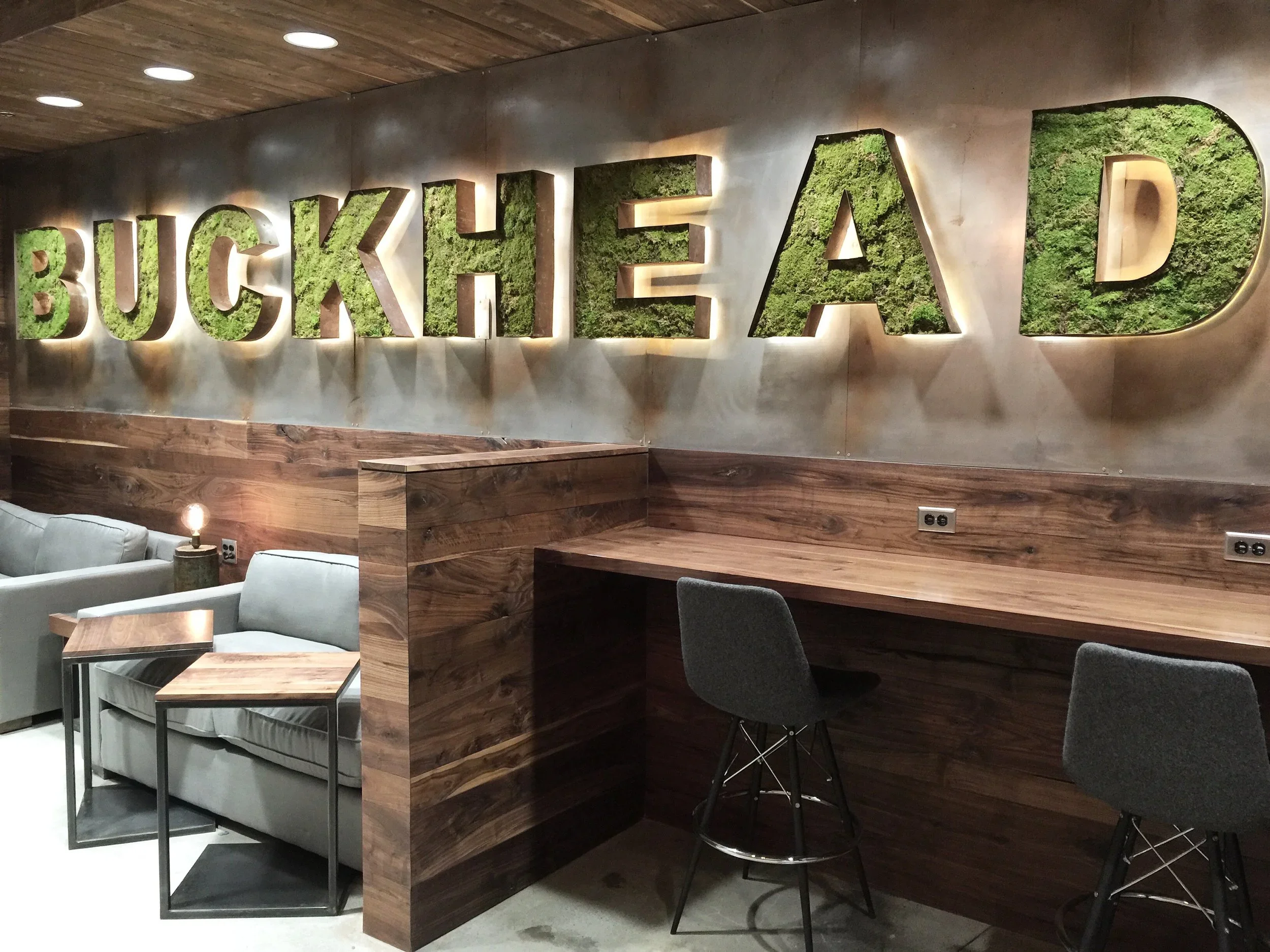Custom hospitality wall with illuminated dimensional lettering, wood finishes, and branded interior fabrication.