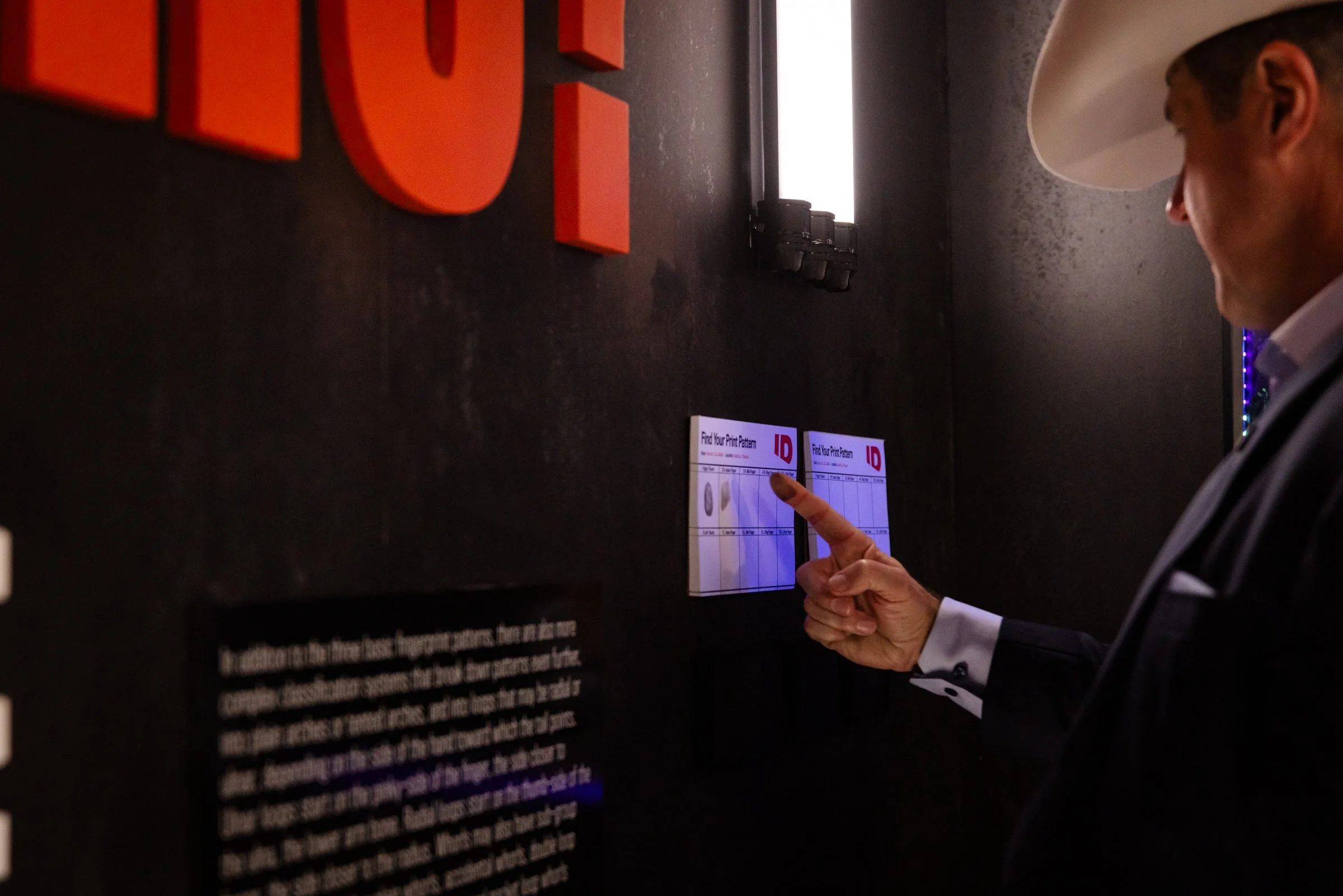 Visitor using interactive wall display with custom graphics, lighting, and branded exhibit design.