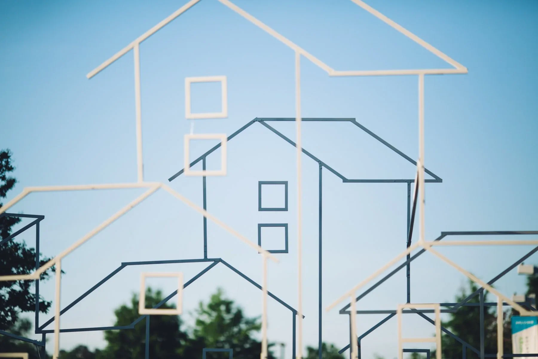 Outdoor wireframe house installation with custom scenic structures for an experiential event.