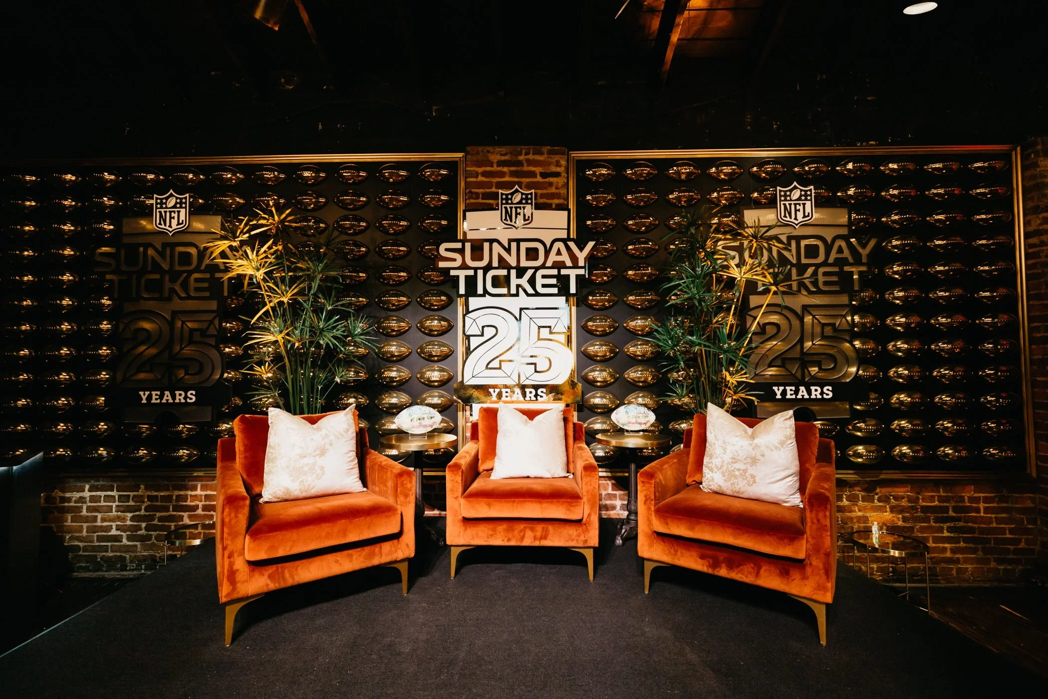 Branded lounge photo moment with custom backdrop, seating, and anniversary event graphics.