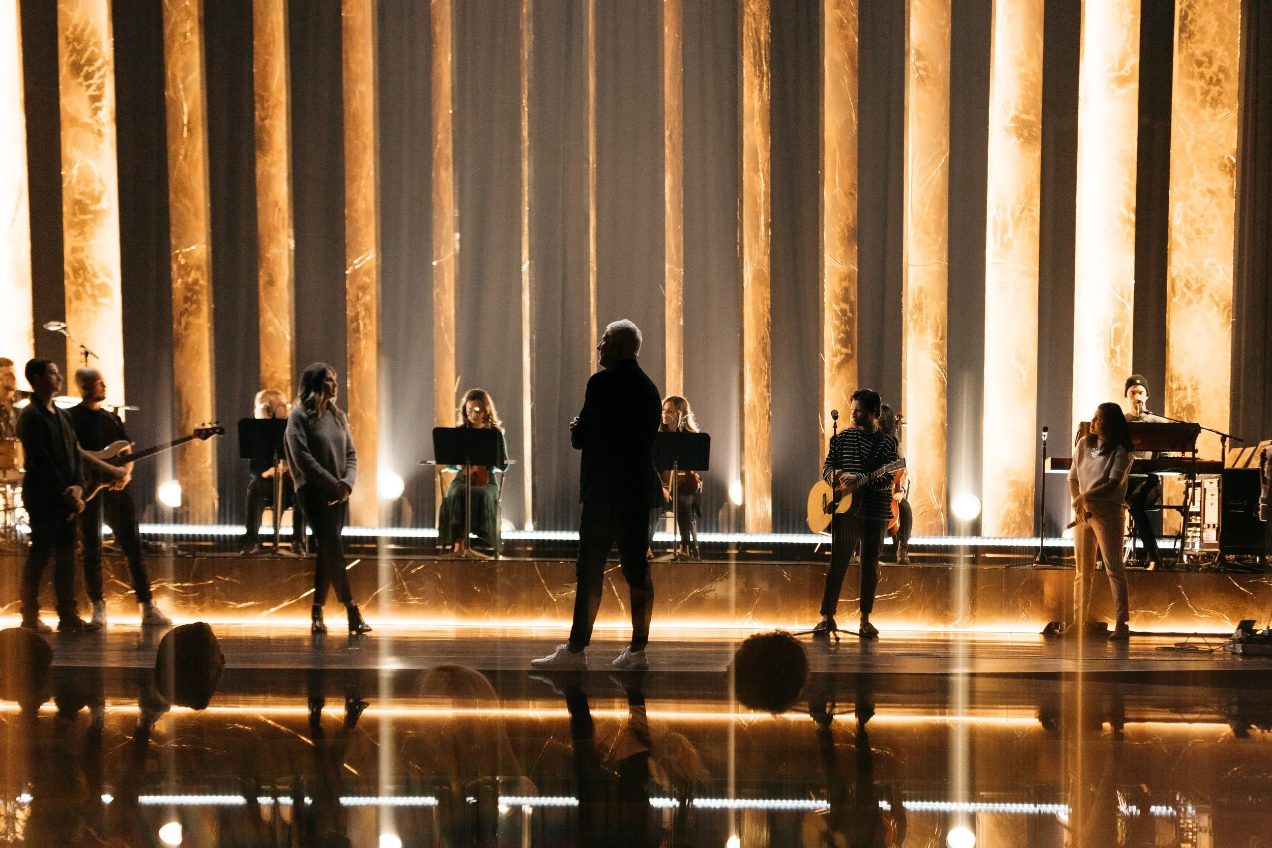 Live performance stage with illuminated vertical scenic panels and custom lighting design.