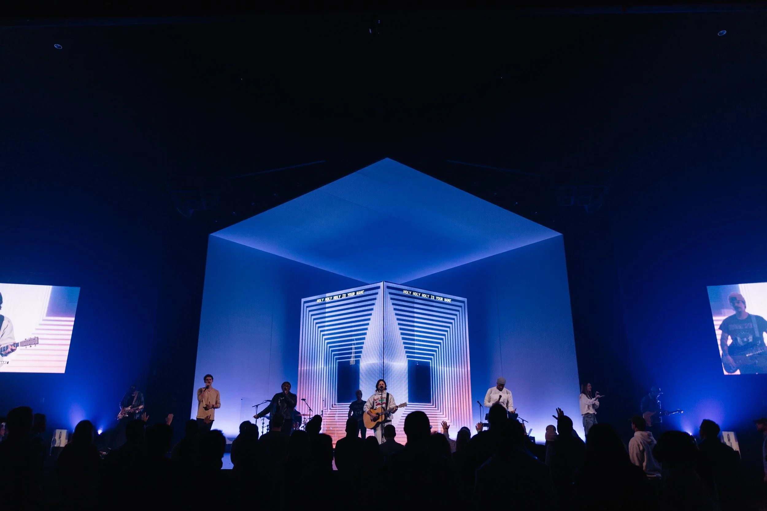 Large geometric stage portal with projection mapping and blue event lighting.