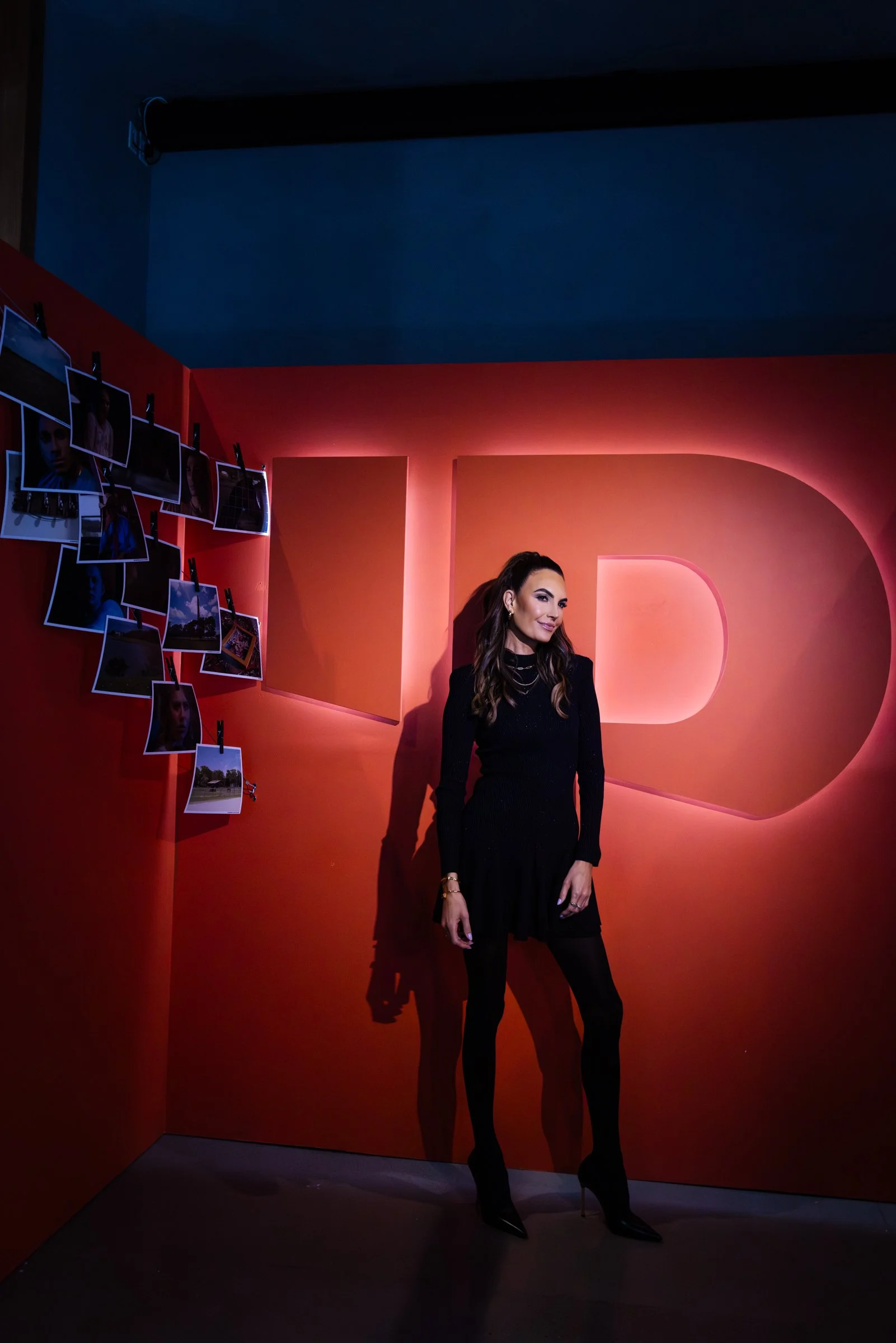 Custom branded photo moment with dimensional logo wall, red scenic backdrop, and event display lighting.