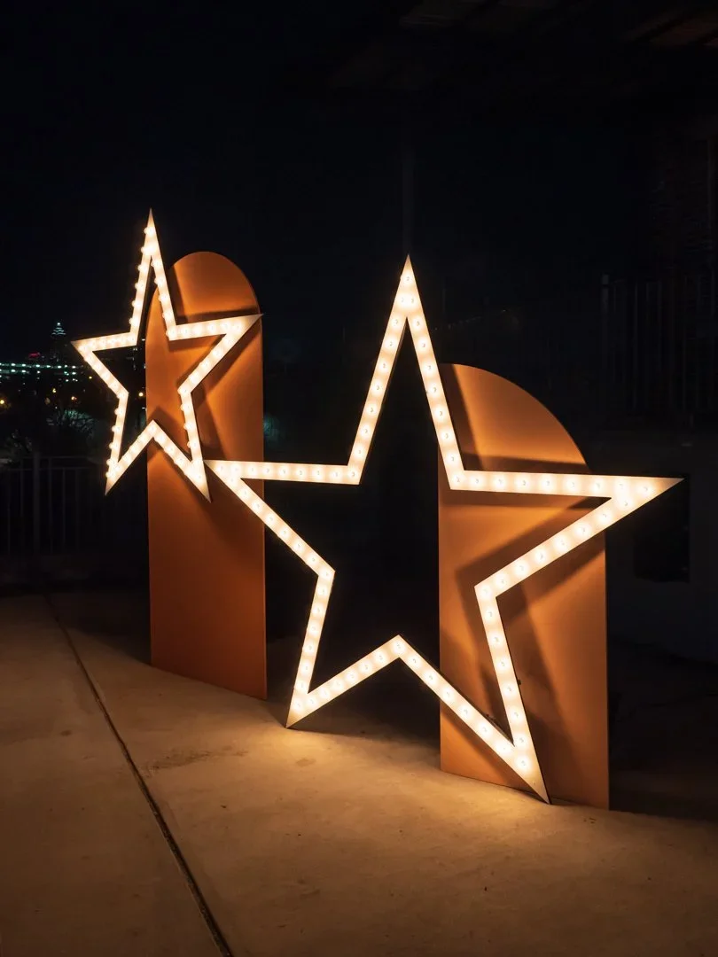 Custom illuminated star props with marquee lighting for branded event display and photo opportunity.