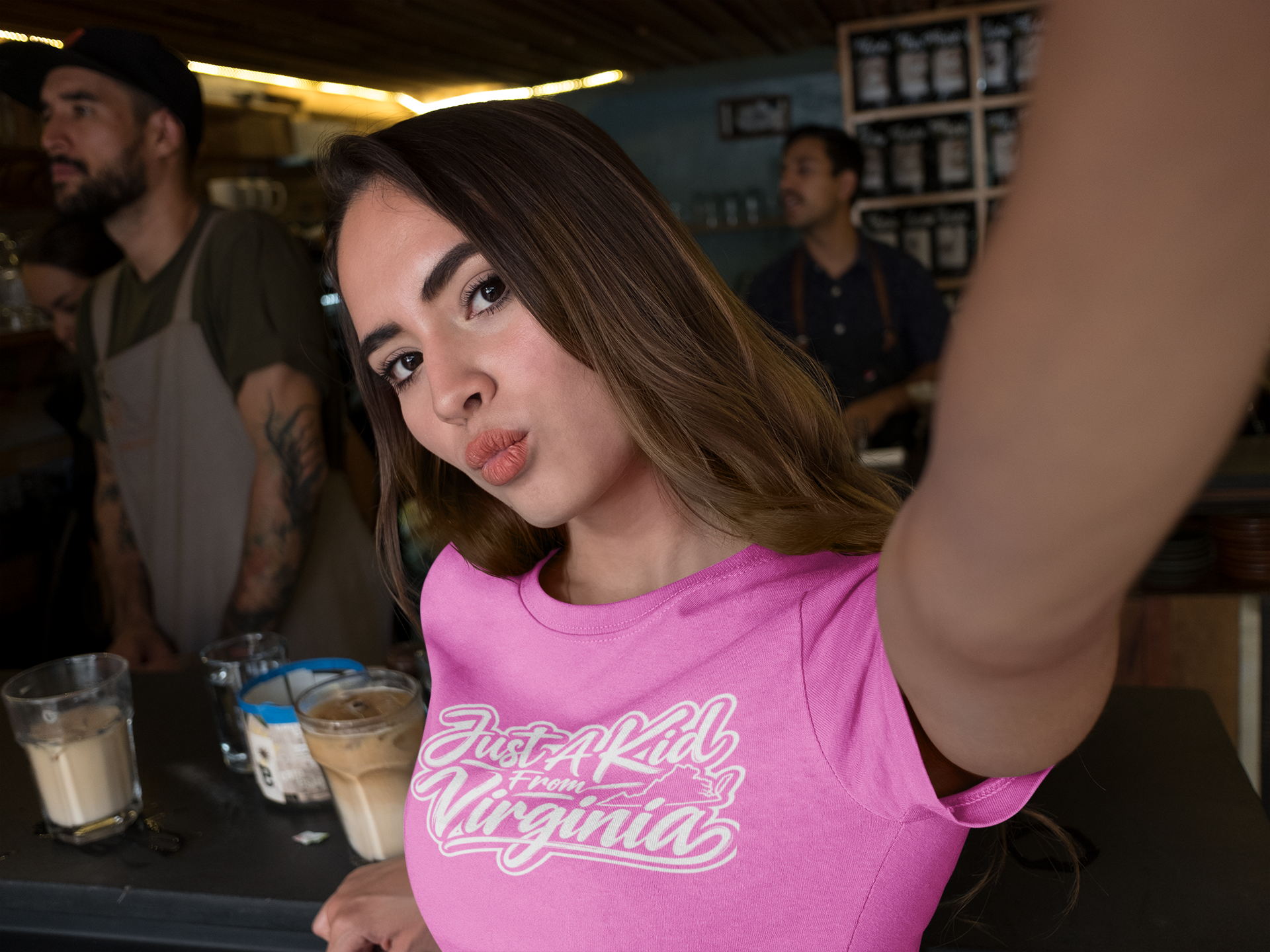 woman-taking-a-selfie-while-at-a-coffee-counter-bar-wearing-a-tshirt-a17049.png