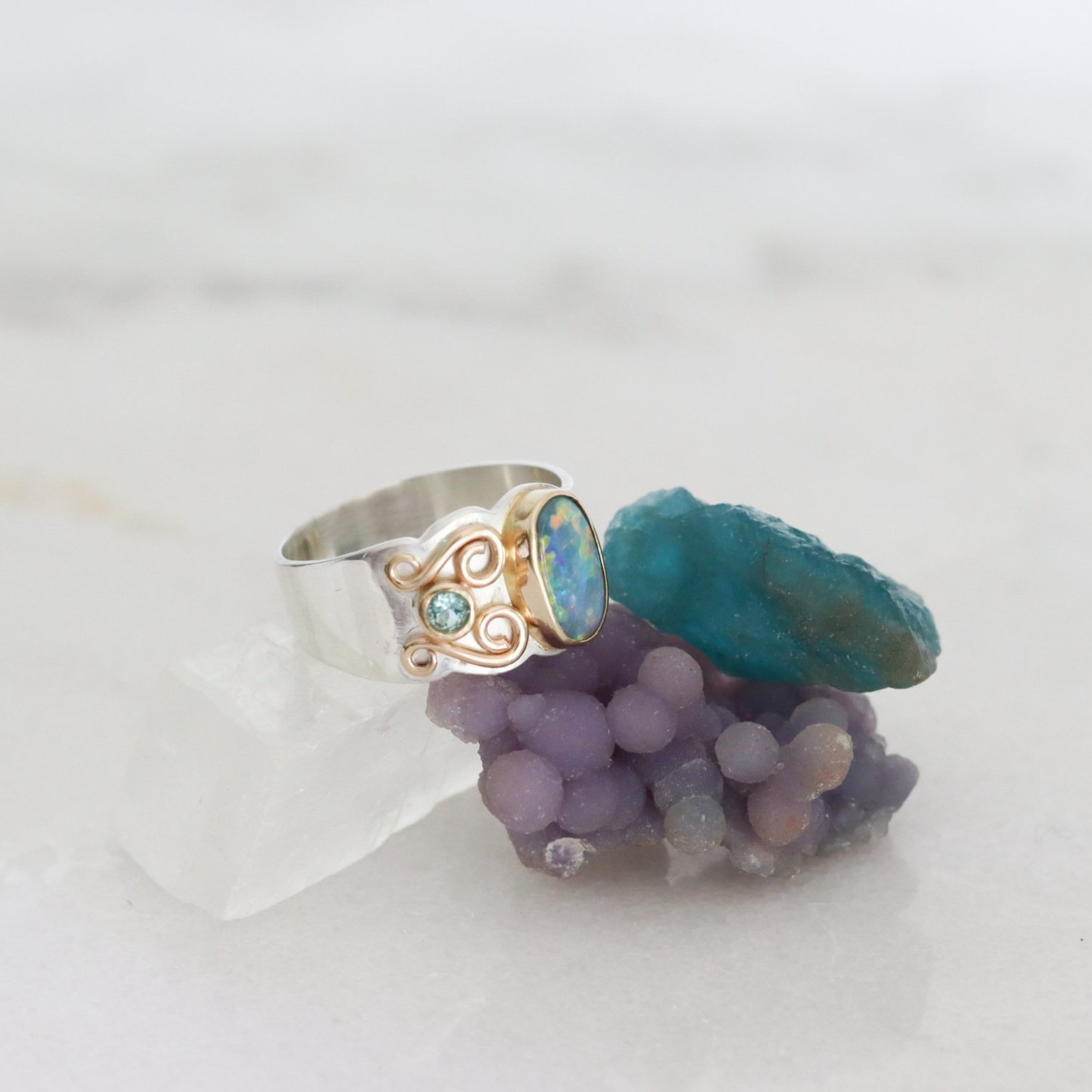 large silver gold and opal ring sitting on stones