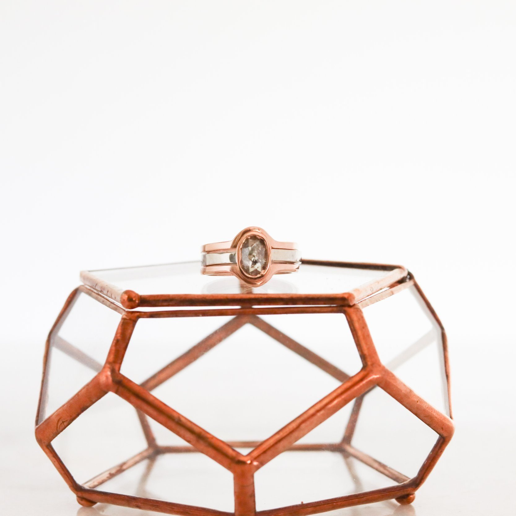 salt and pepper diamond three ring set sitting on a geometric ring box