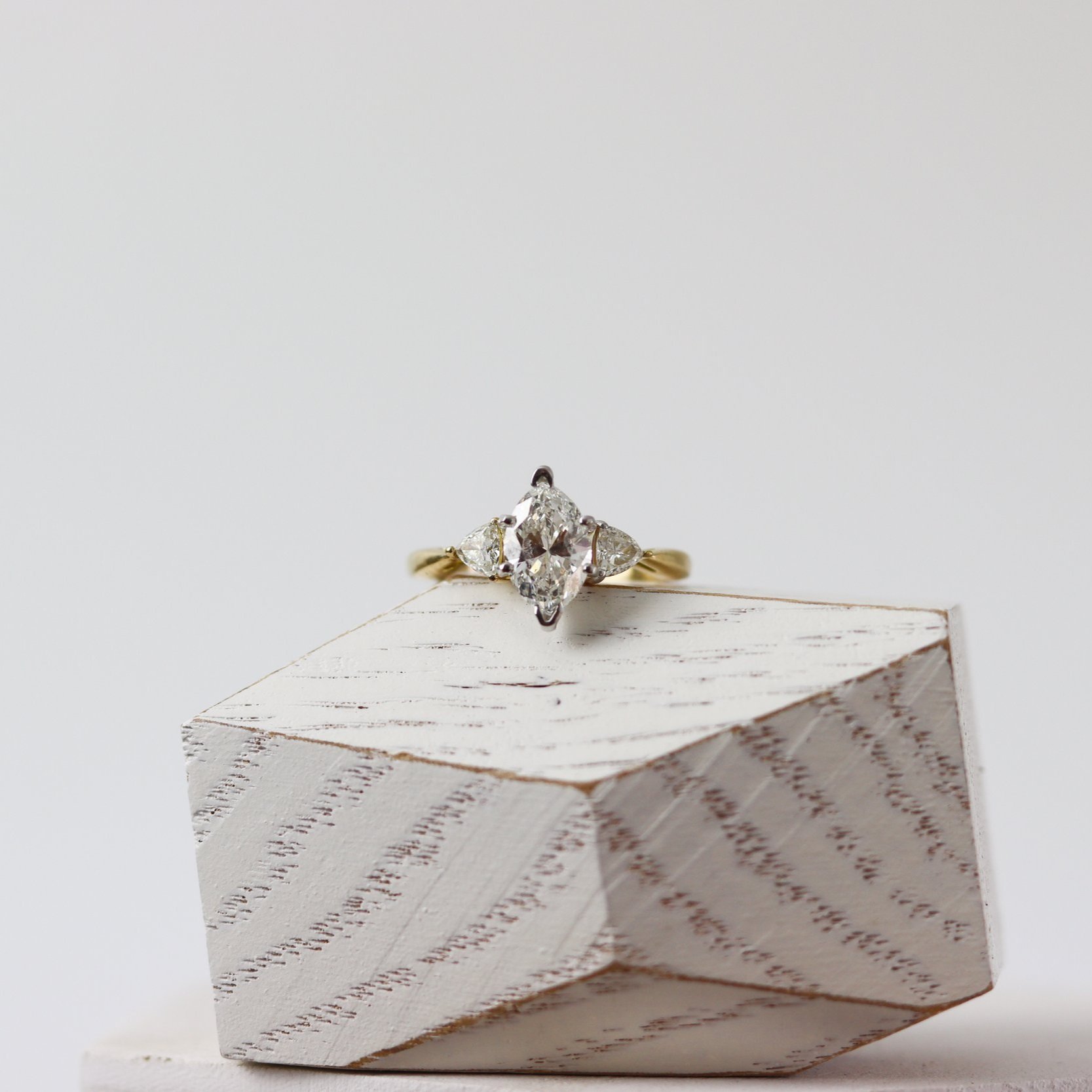 three stone marquise engagement ring on a wooden block
