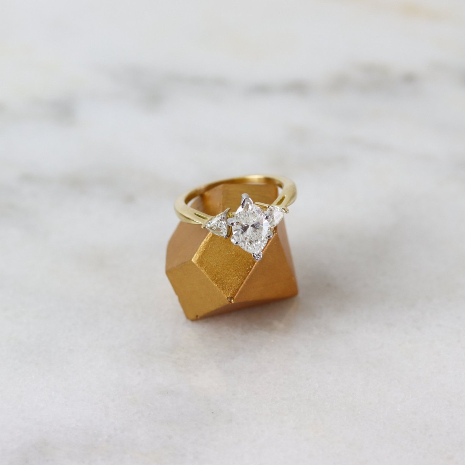 marquise and trillion engagement ring balanced on a concrete diamond