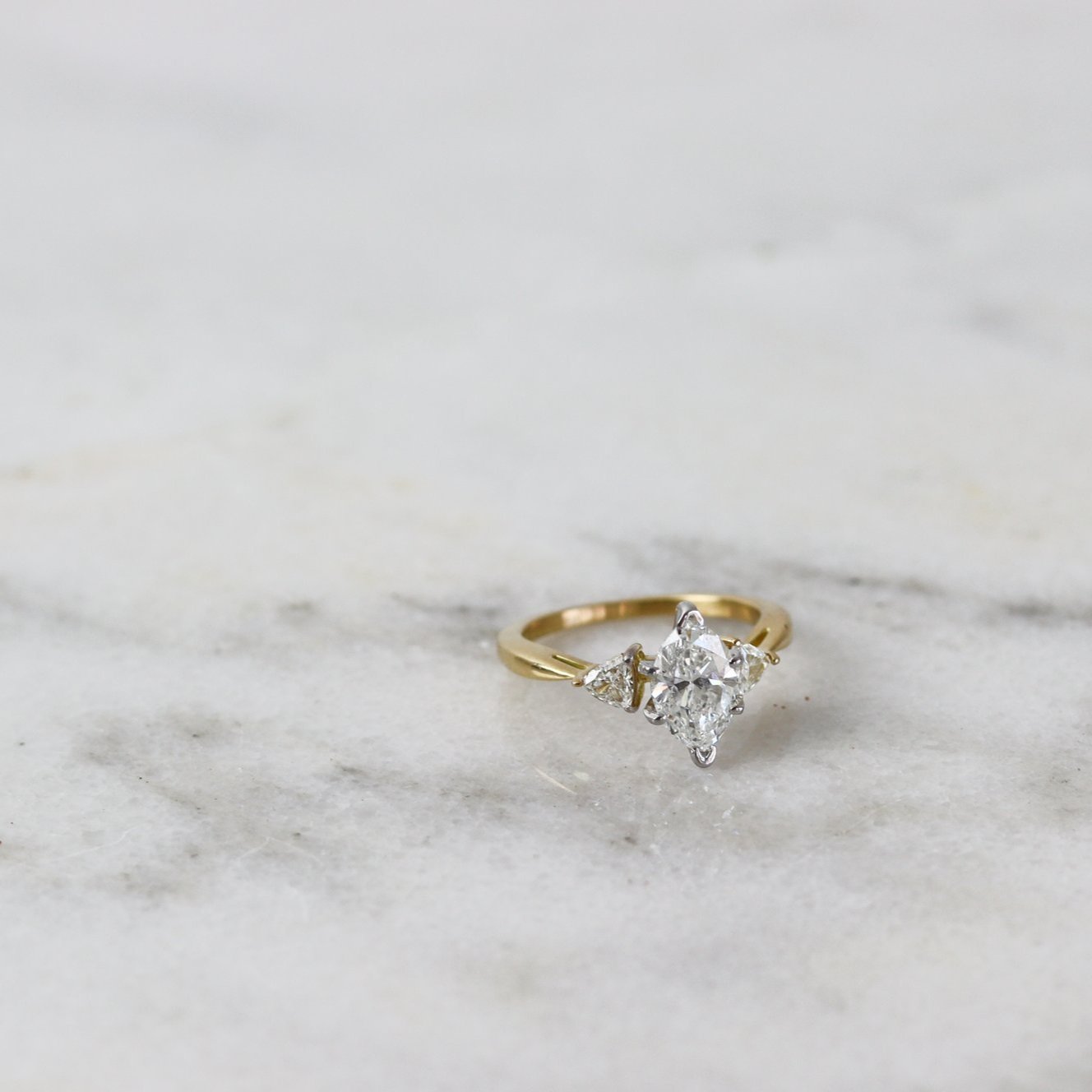 marquise and trillion diamond engagement ring on marble tile