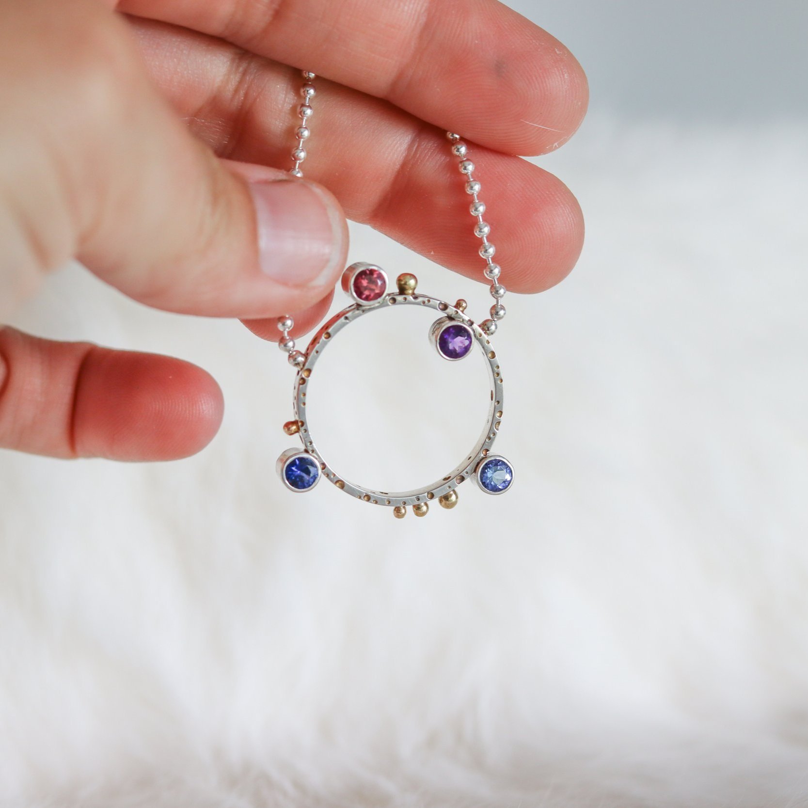 Circle Pendant with Four Birthstones held in Hand