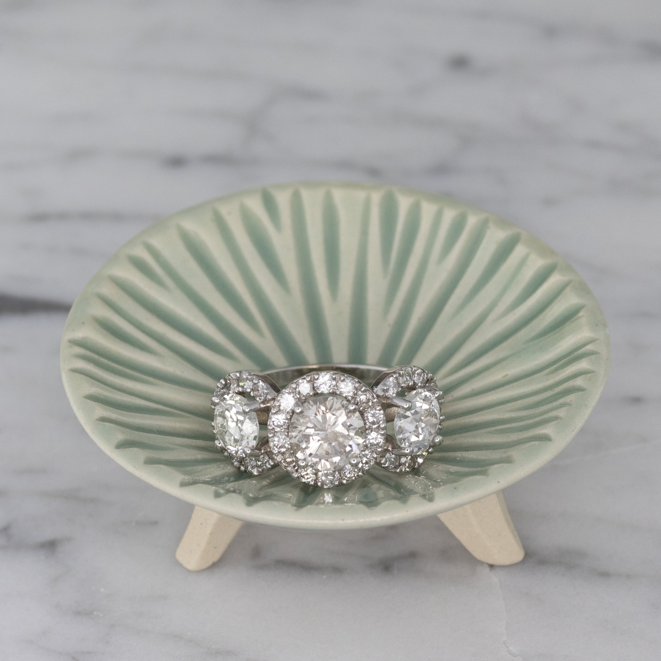 three stone halo ring in green bowl