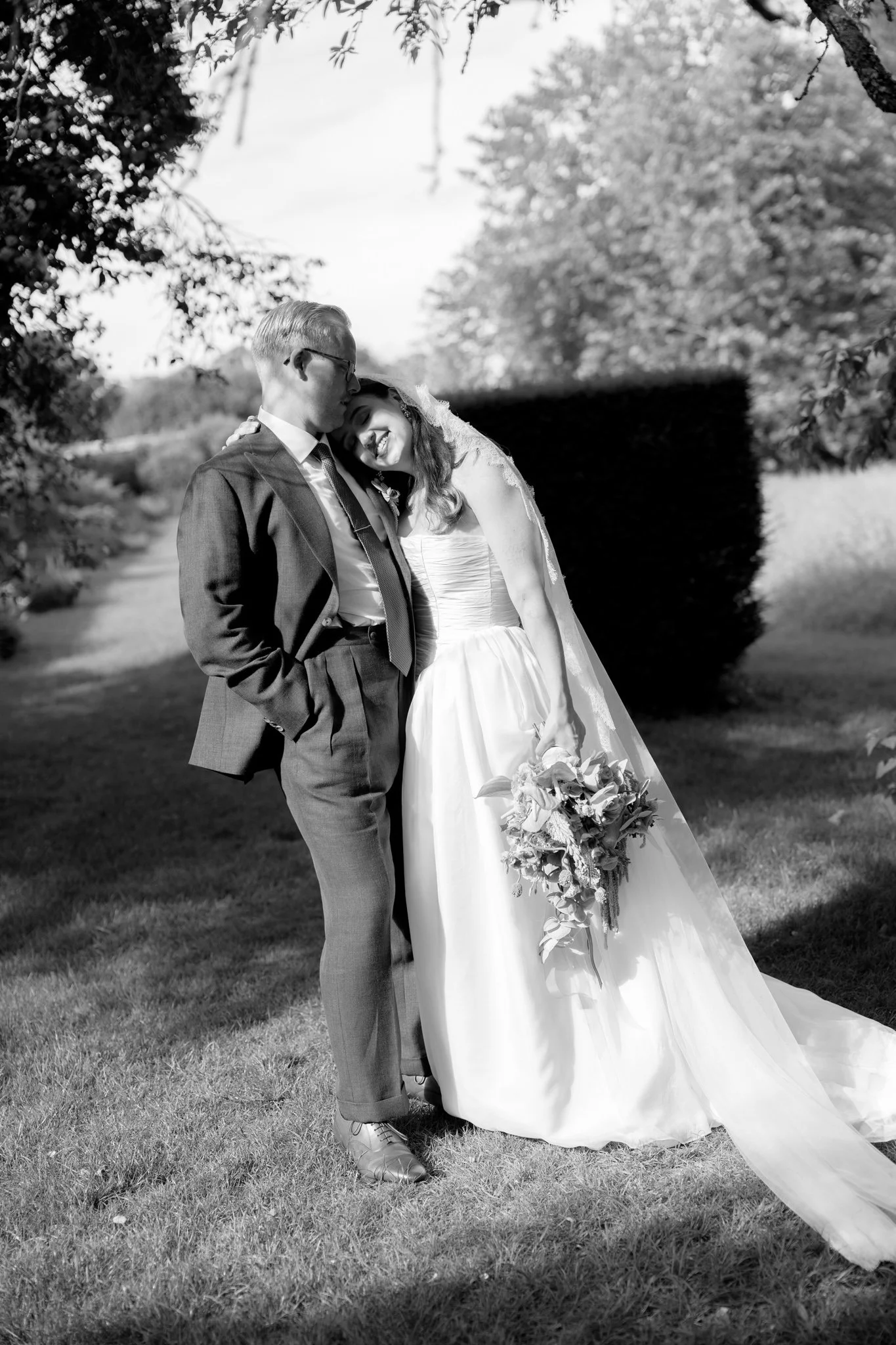 a bride and groom in hampshire standing in the sunshine the bride is leaning on the groom