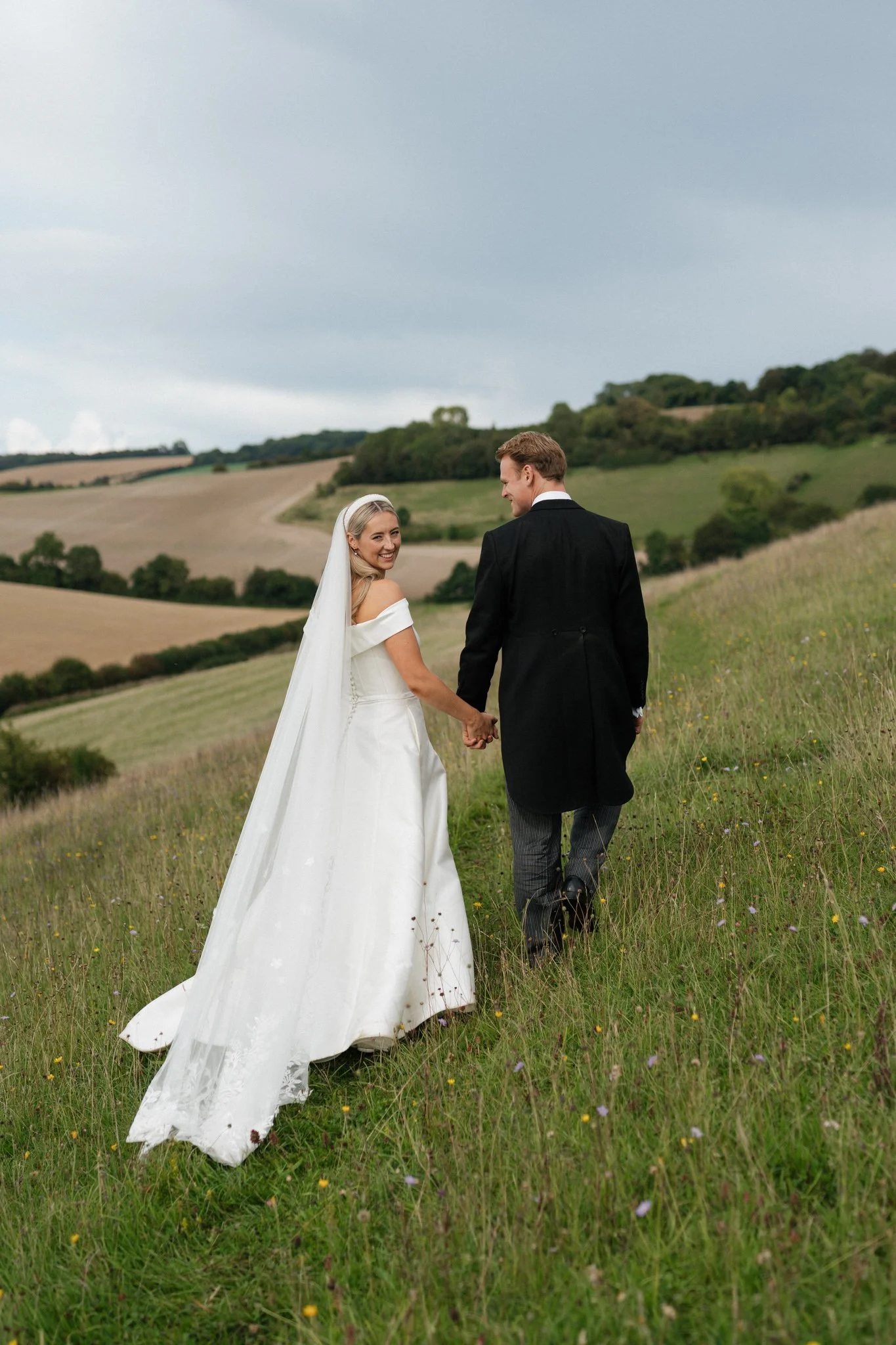bride and groom walking through fields