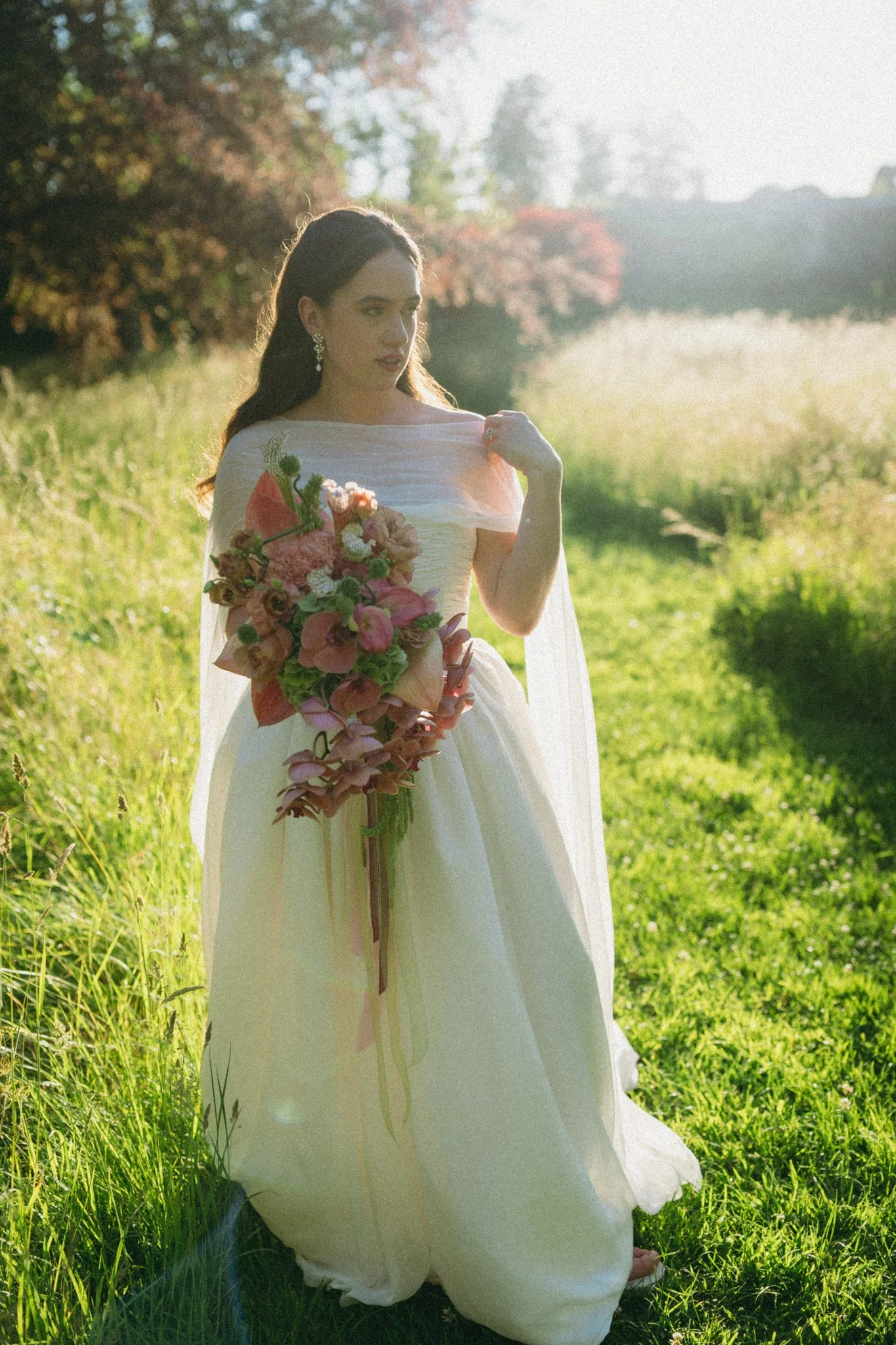a bride in hampshire with the sun behind her holding a bouquet