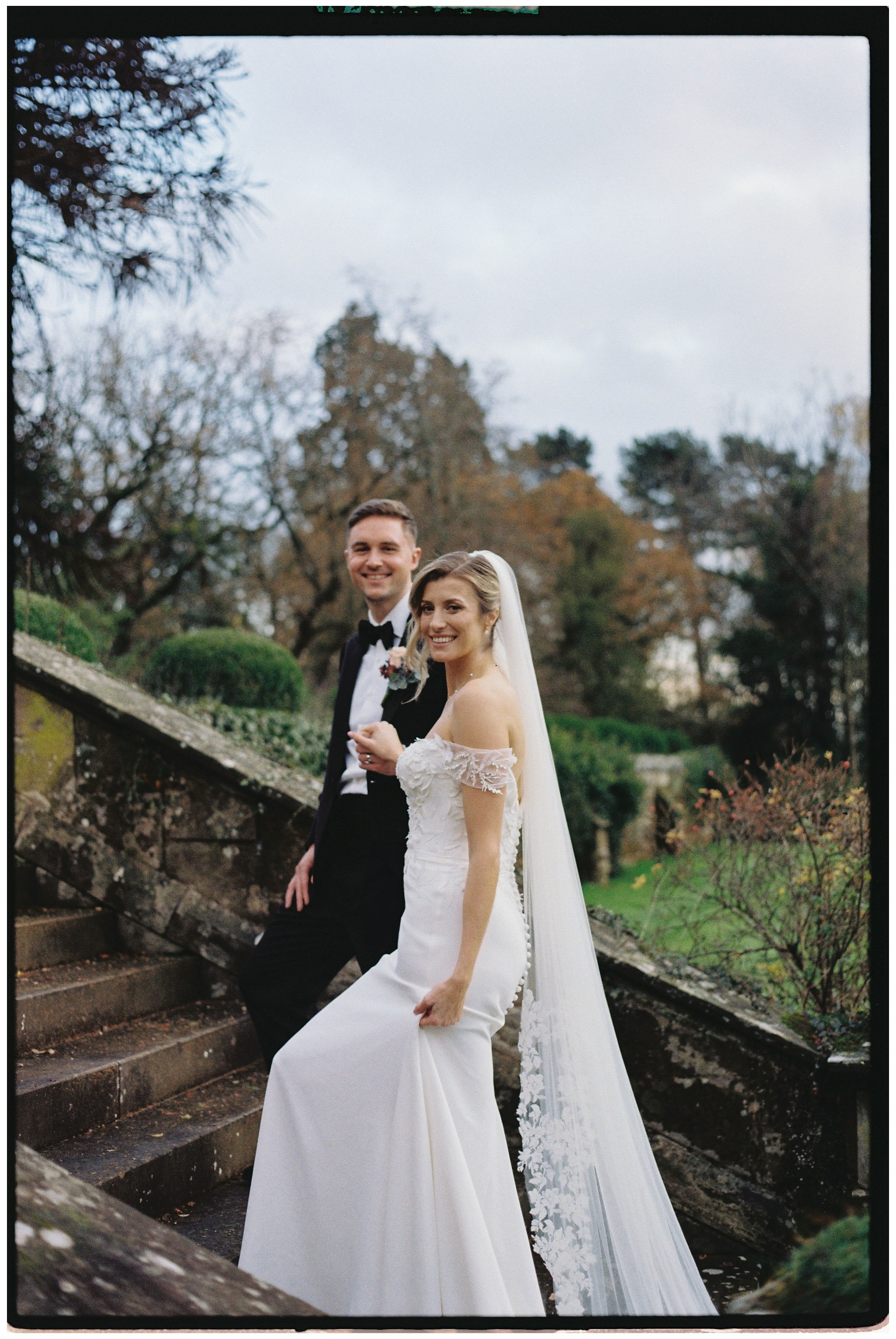 a bride and groom walk up the stairs at hampton manor. the image was shot on film on a vintage camera