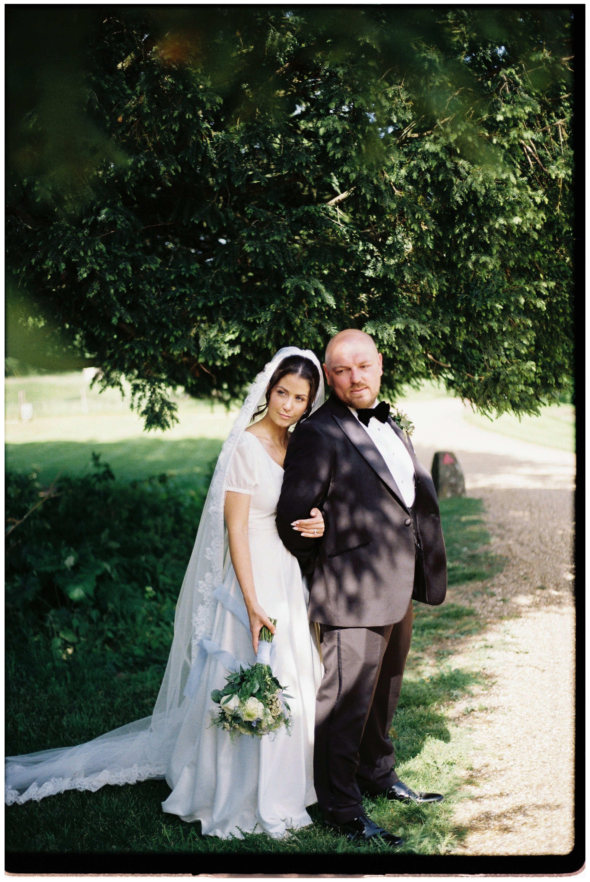 a bride and groom stood under a tree