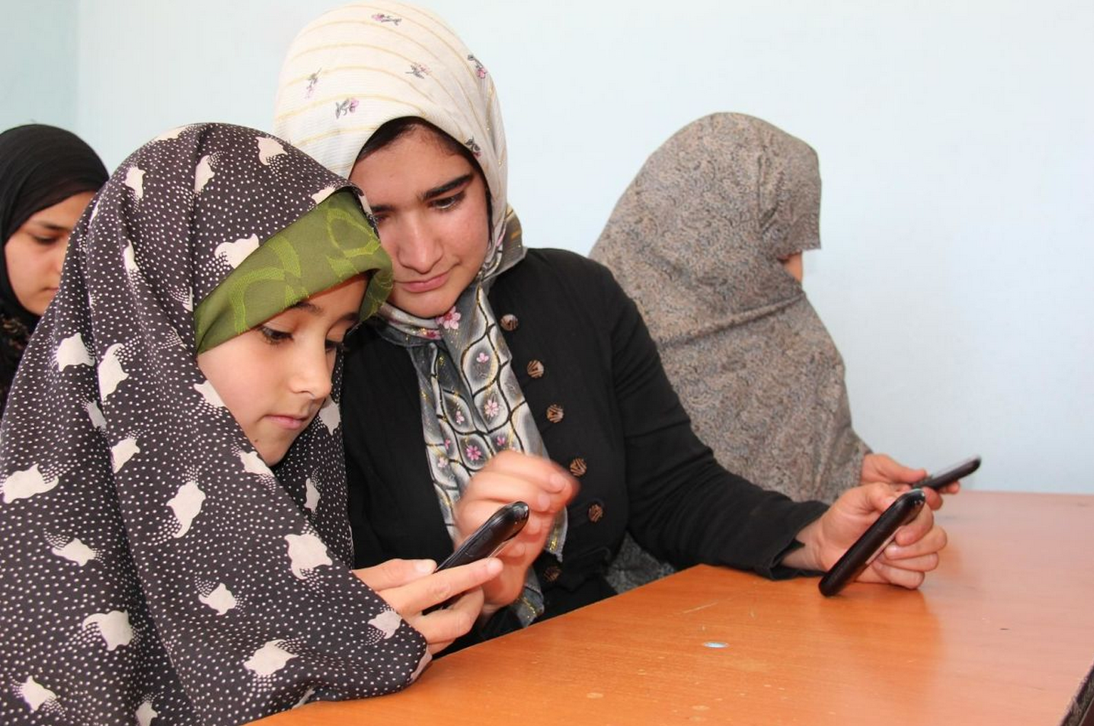 Afghan girls learning to read with mobile phones.