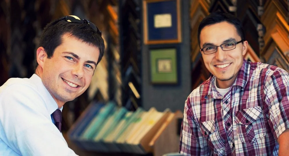 South Bend's mayor pete buttigieg (left) takes a photo with the owner of the frame factory, salvador moya (right).